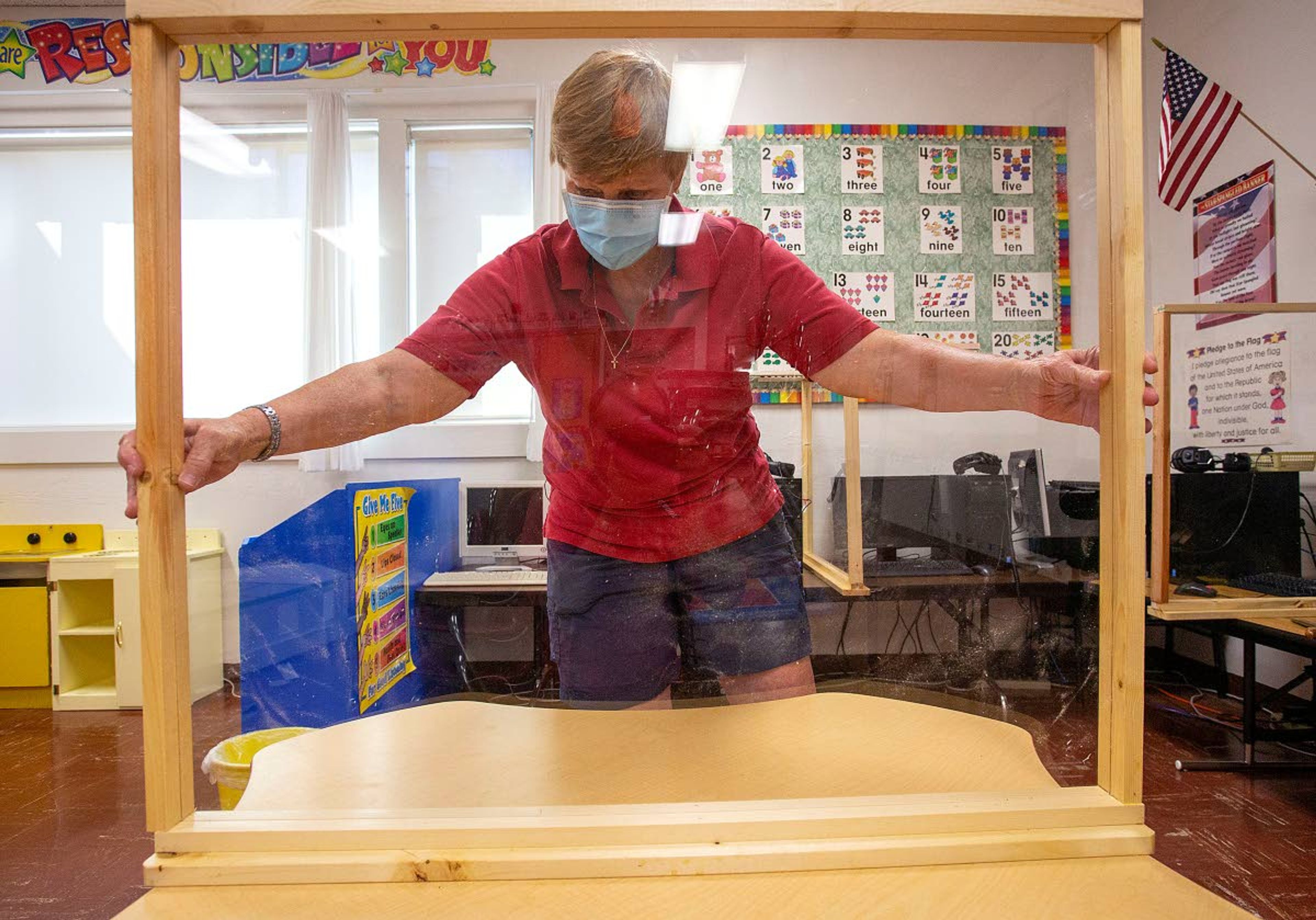 Principal Jennifer Beller sets a plastic divider on a table on Monday at Saint Mary's School in Moscow. The divider will help prevent the spread of the coronavirus while two students sit across from each other at a table.