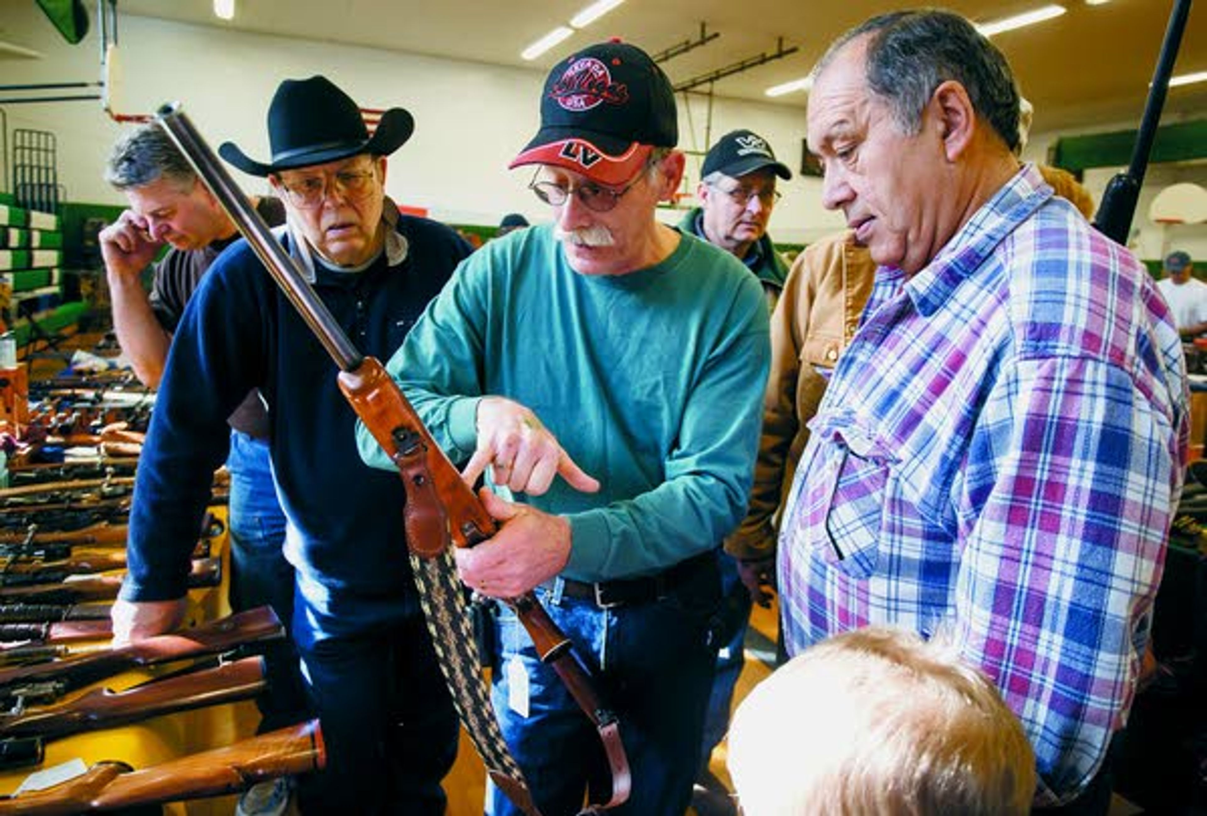 Mike Gilmore, center, of Potlatch, points out a detail on a rifle to Ken Jeffrey, right, of St. Maries, Idaho, and Don Harnish, of Deary, during the Potlatch gun show on Sunday at Potlatch Elementary School.