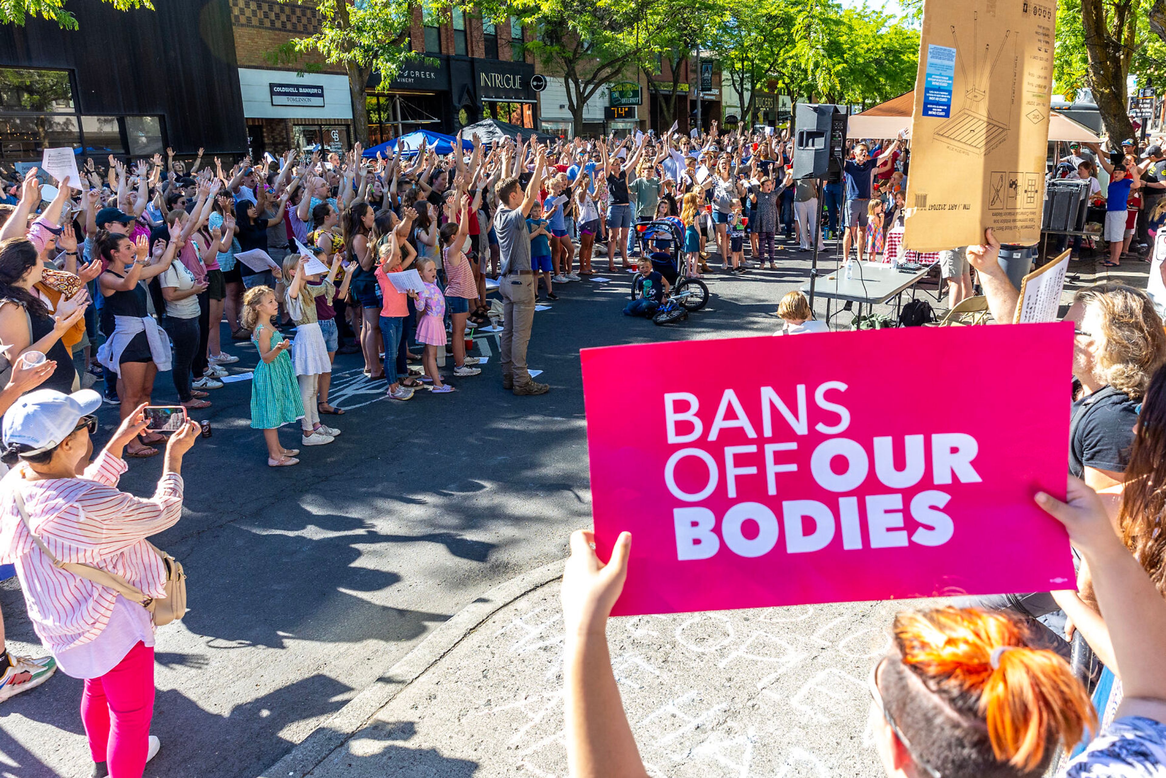 People hold up their hands as counter protesters hold signs during a block party celebrating the anniversary of the overturning of Roe v. Wade on Main Street Monday in Moscow.