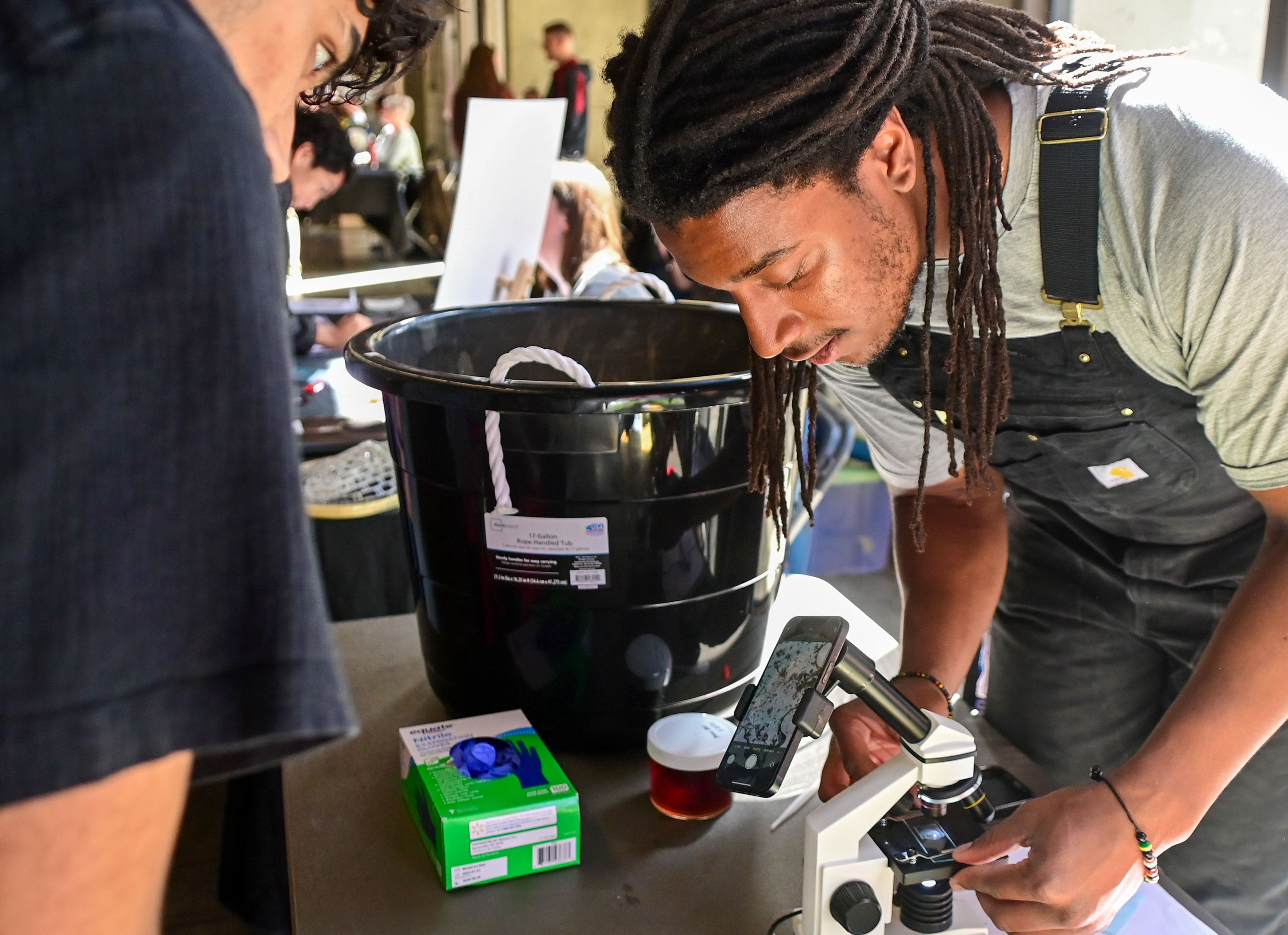 Malachi Ledbetter, right, a sophomore at Washington State University and member of WSU’s organic agriculture club, shows the activity in compost as part of an Earth Day event at Beasley Coliseum in Pullman on Sunday.