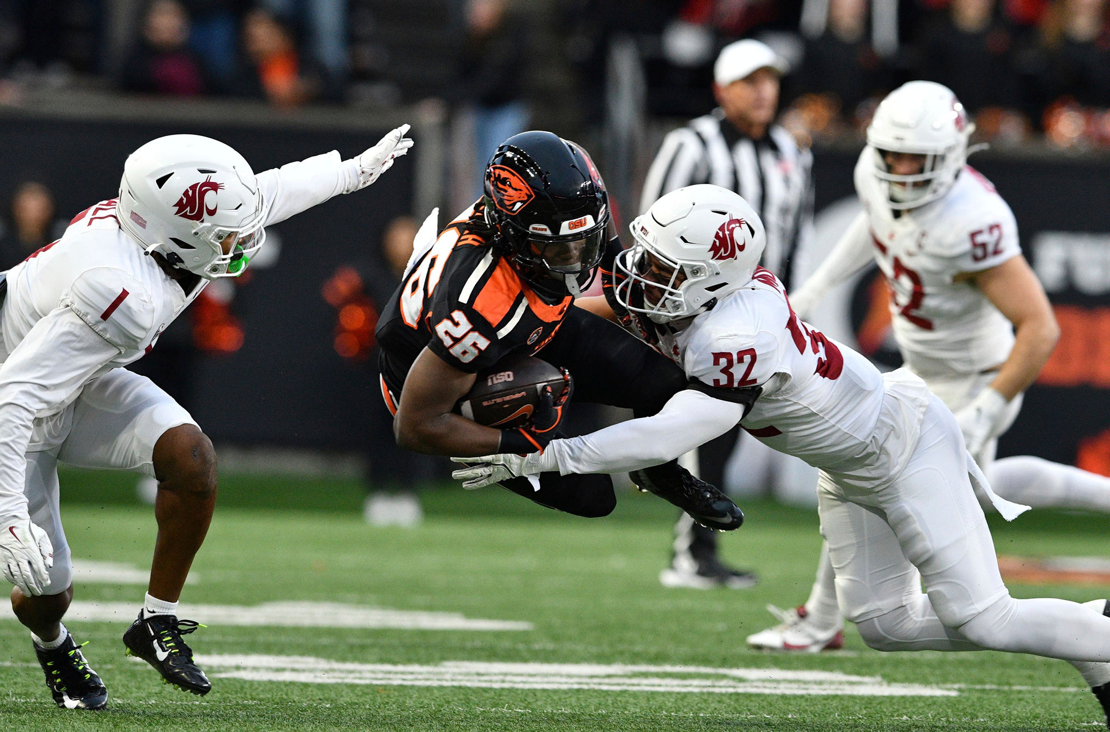 Washington State defensive backs Stephen Hall (1) and Tanner Moku (32) tackle Oregon State running back Salahadin Allah (26) during the first half of an NCAA college football game Saturday, Nov. 23, 2024, in Corvallis, Ore. (AP Photo/Mark Ylen)