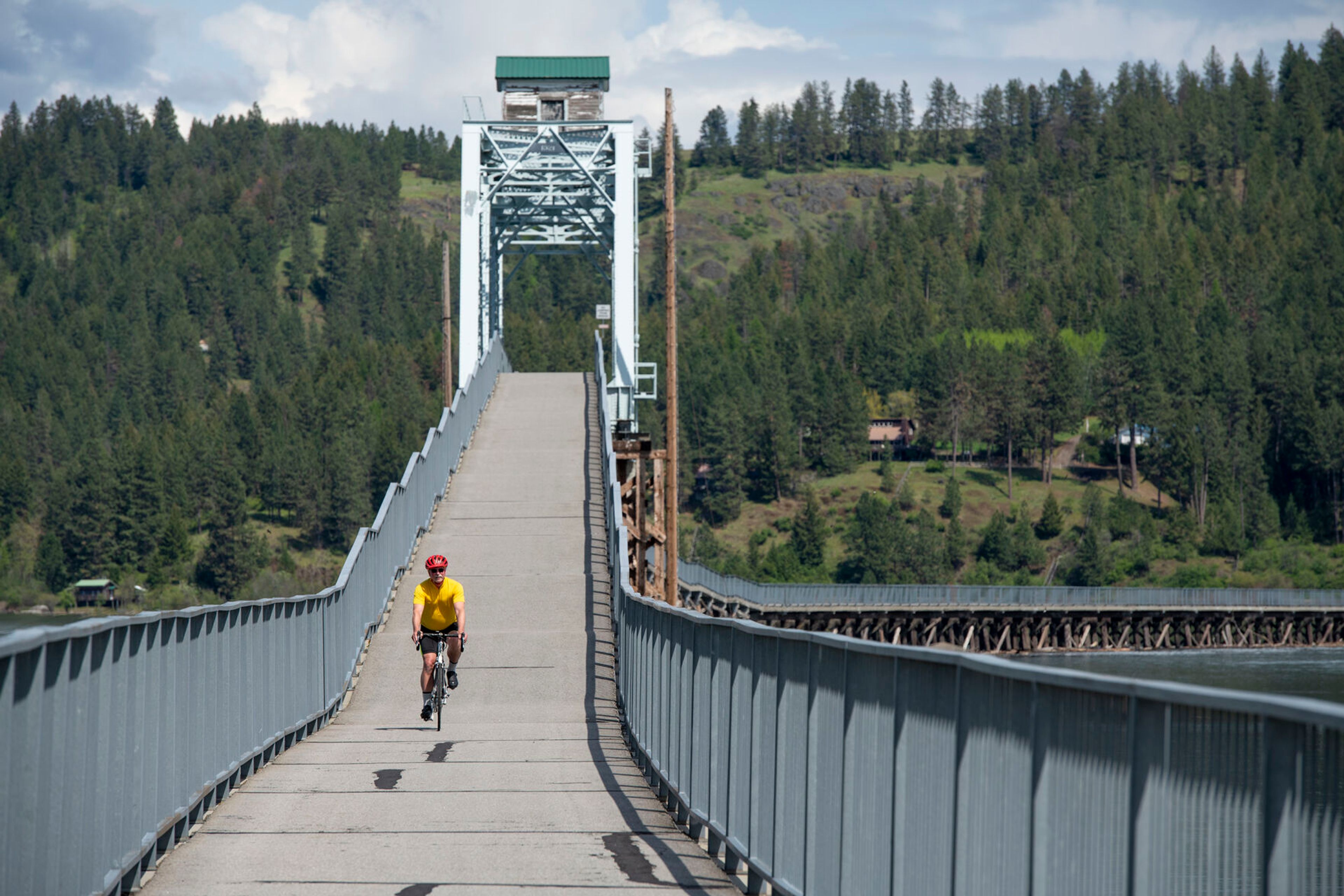 A cyclist rides across a bridge on the Trail of the Coeur d’Alene.