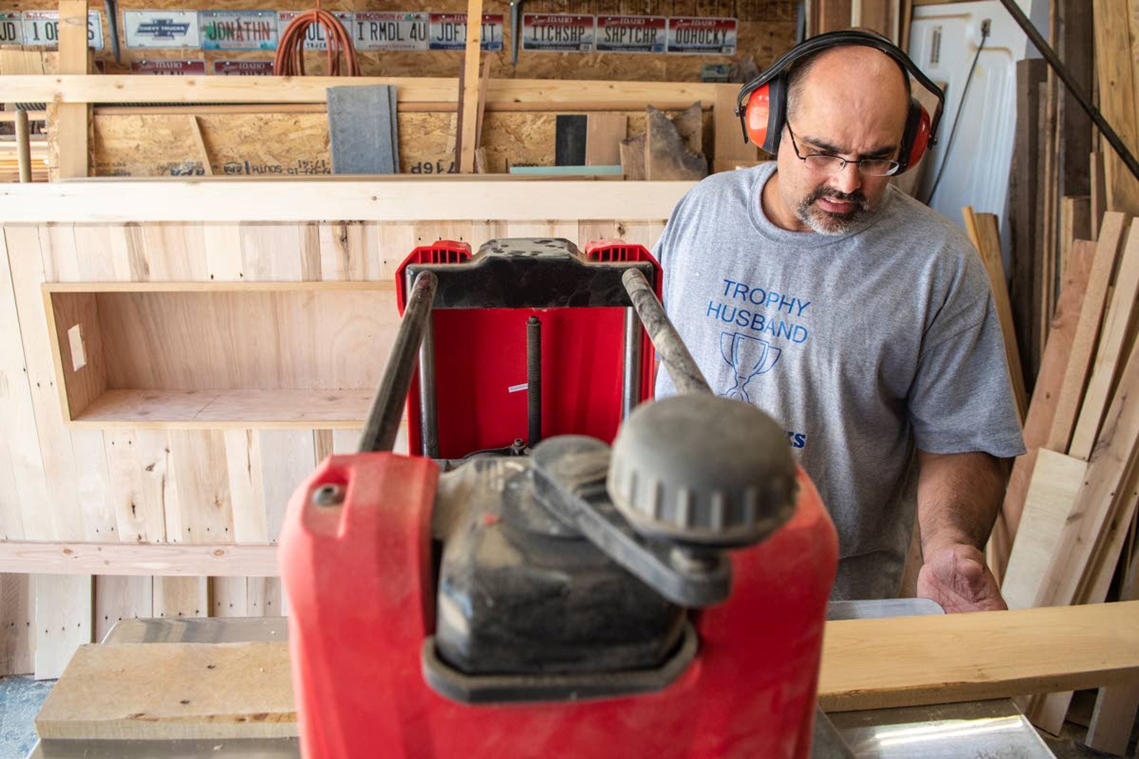 Poulos runs a piece of pallet wood through a wood planer to smooth and thin it out before moving on with his project.