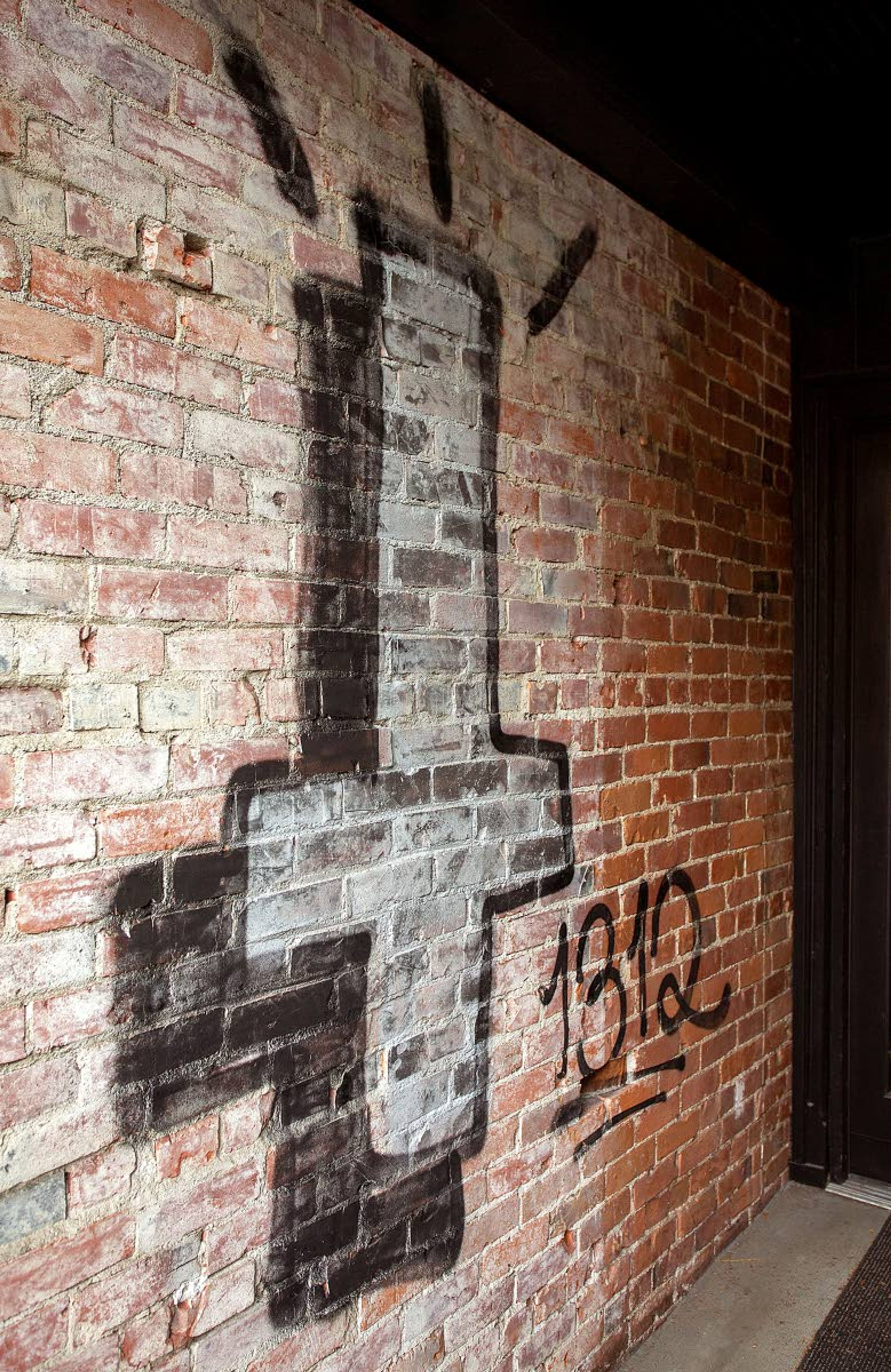 Graffiti, including an inverted cross and the number “1312,” is seen outside Roman Roads Press on Monday on East Third Street in Moscow. Graffiti was also painted on the wall of Canon Press on North Main Street.