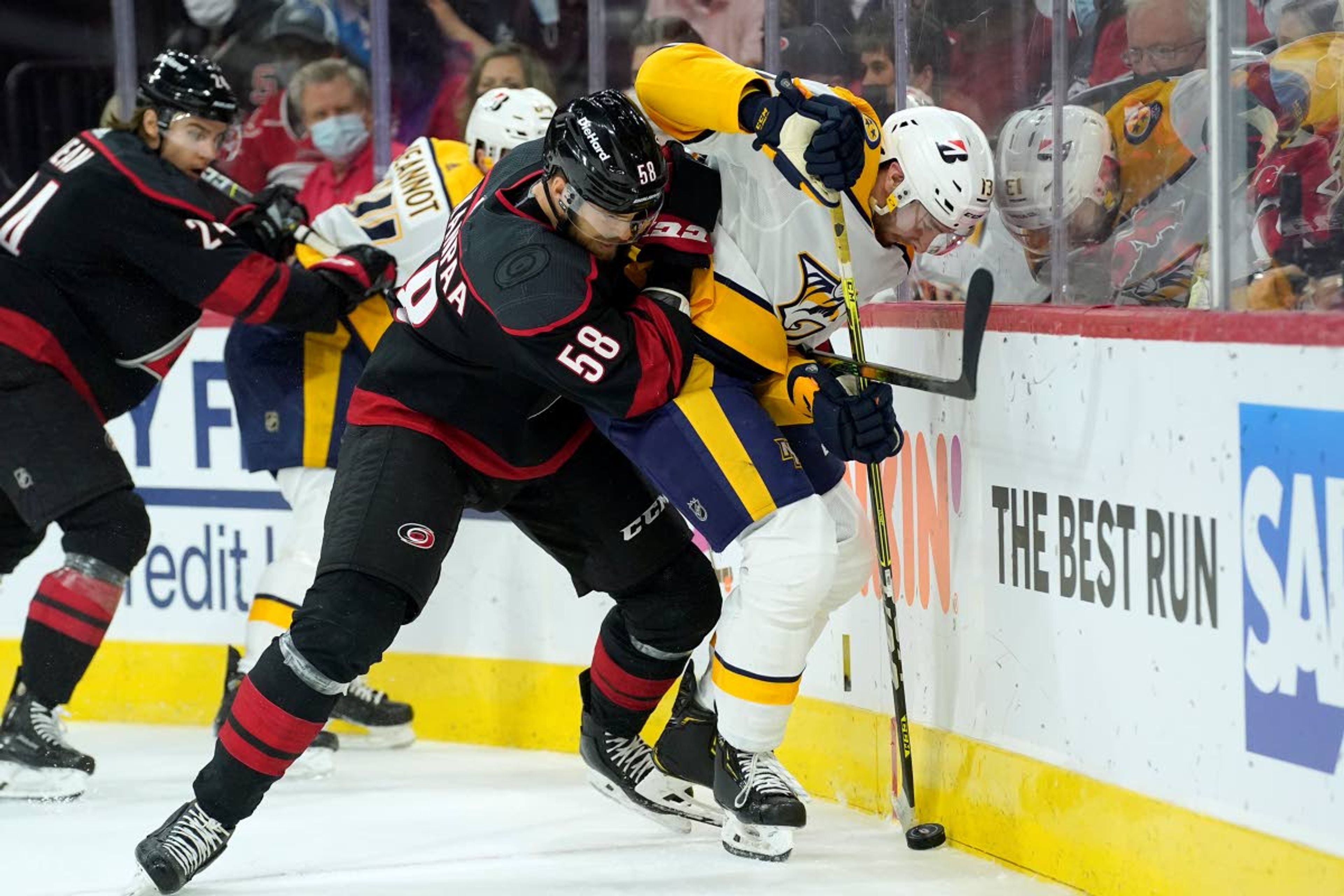 Carolina Hurricanes defenseman Jani Hakanpaa (58) and Nashville Predators center Yakov Trenin (13) skate for the puck during the first period in Game 5 of an NHL hockey Stanley Cup first-round playoff series in Raleigh, N.C., Tuesday, May 25, 2021. (AP Photo/Gerry Broome)