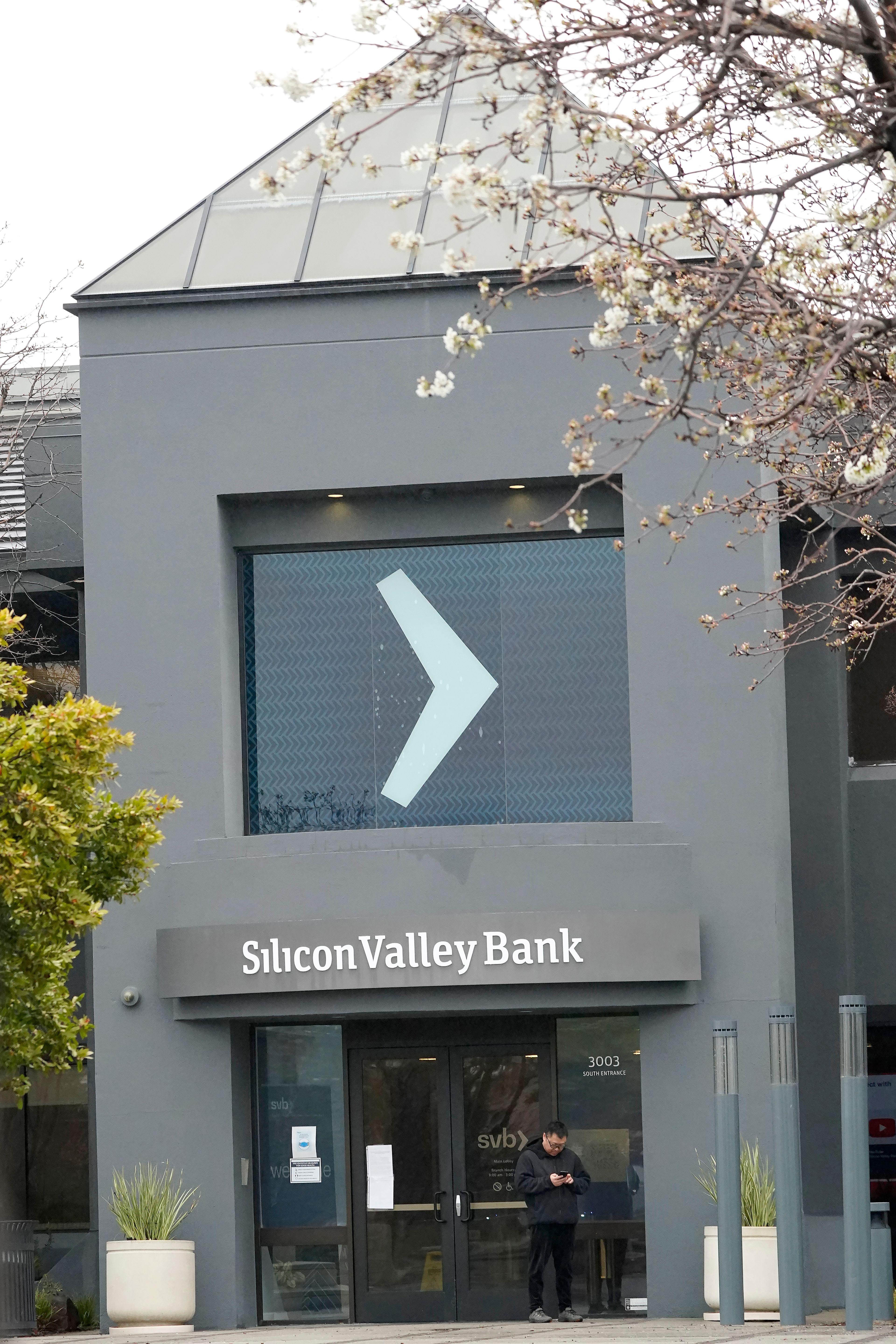 A person stands outside of an entrance to Silicon Valley Bank in Santa Clara, Calif., Friday, March 10, 2023.The Federal Deposit Insurance Corporation is seizing the assets of Silicon Valley Bank, marking the largest bank failure since Washington Mutual during the height of the 2008 financial crisis. The FDIC ordered the closure of Silicon Valley Bank and immediately took position of all deposits at the bank Friday. (AP Photo/Jeff Chiu)