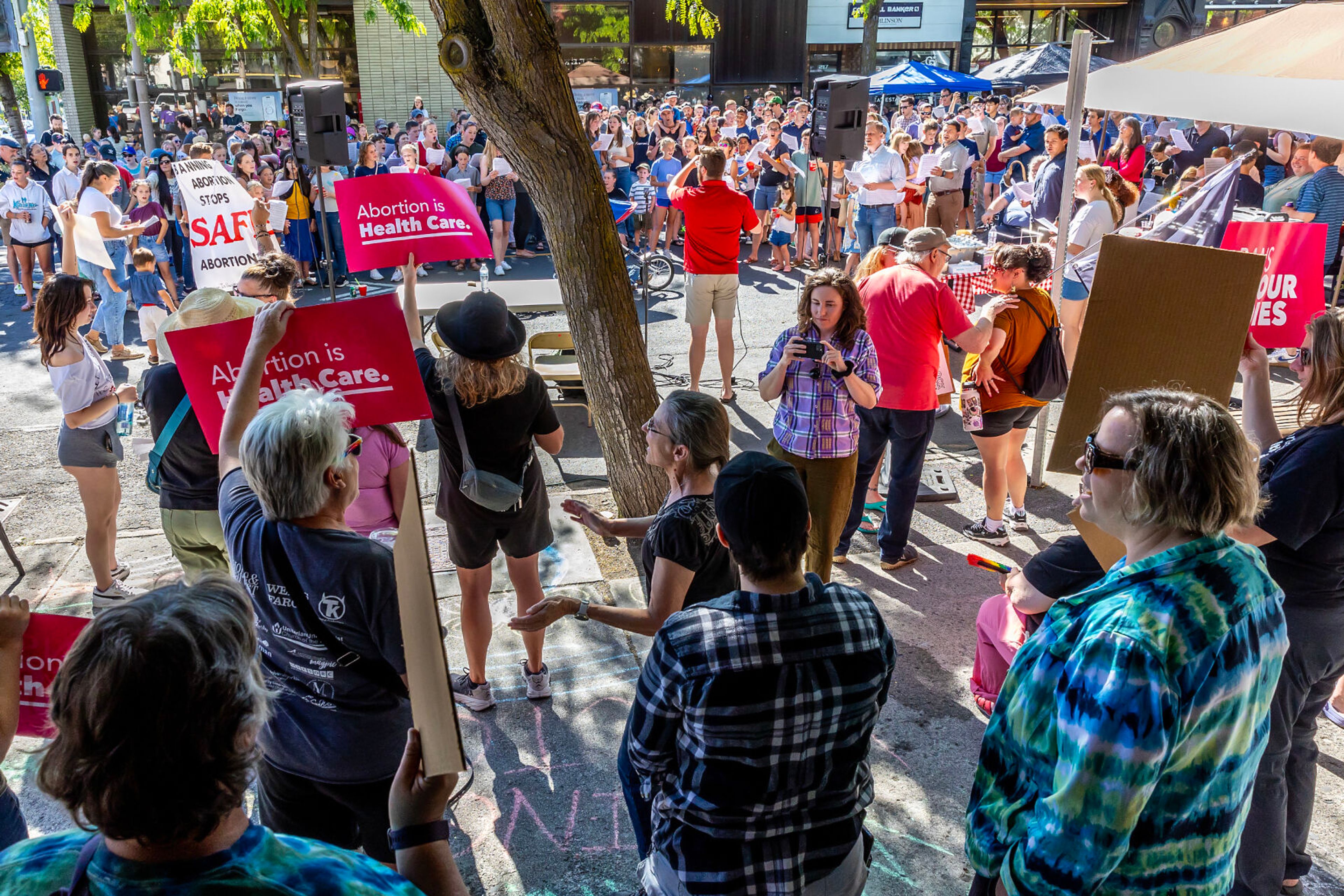 Christ Church members sing as counter protesters start singing “This Land is Your Land” in response as they hold signs during a block party celebrating the anniversary of the overturning of Roe v. Wade on Main Street Monday in Moscow.