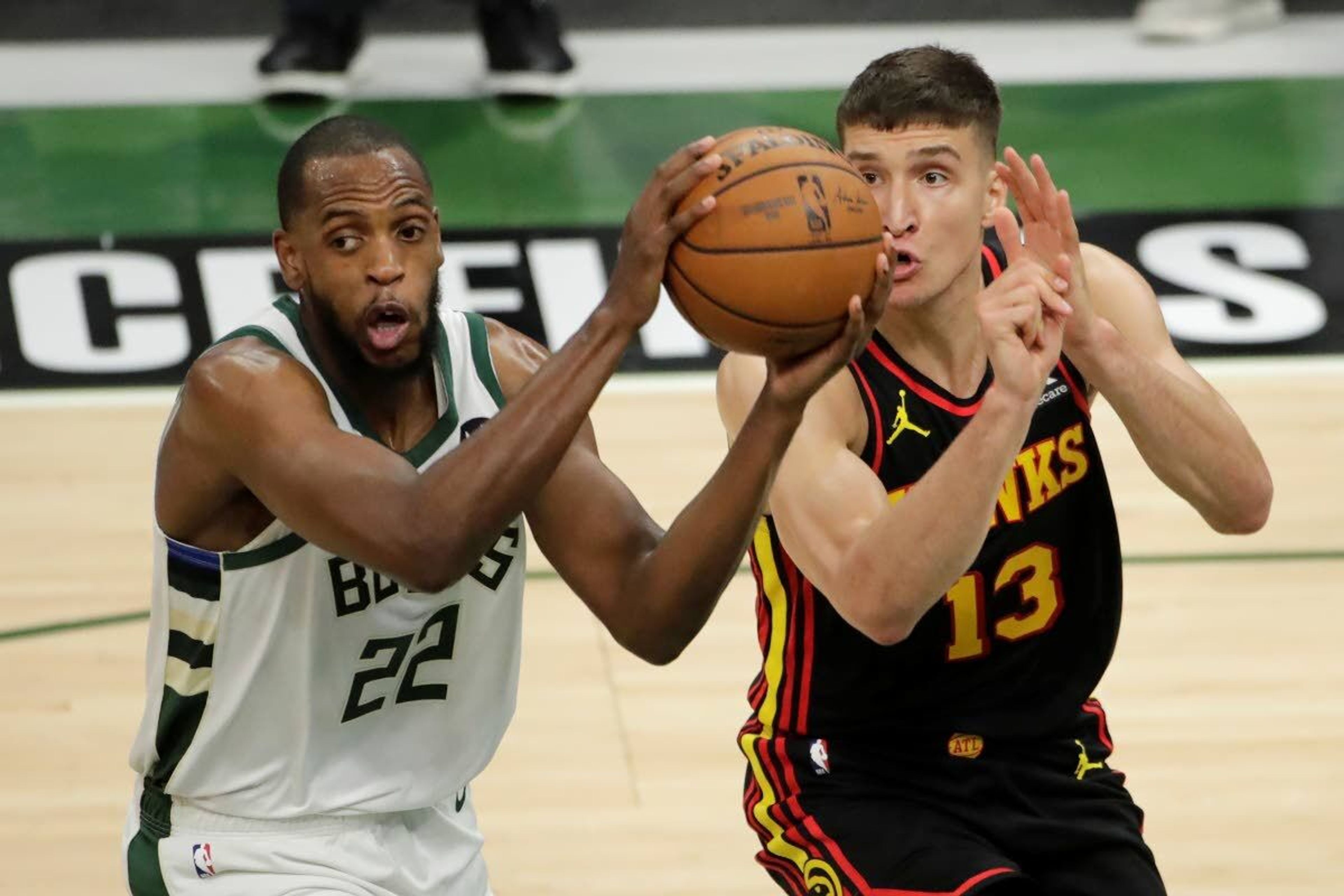 Milwaukee Bucks' Khris Middleton, left, drives to the basket against Atlanta Hawks' Bogdan Bogdanovic, right, during the first half of Game 5 of the NBA Eastern Conference Finals Thursday, July 1, 2021, in Milwaukee. (AP Photo/Aaron Gash)