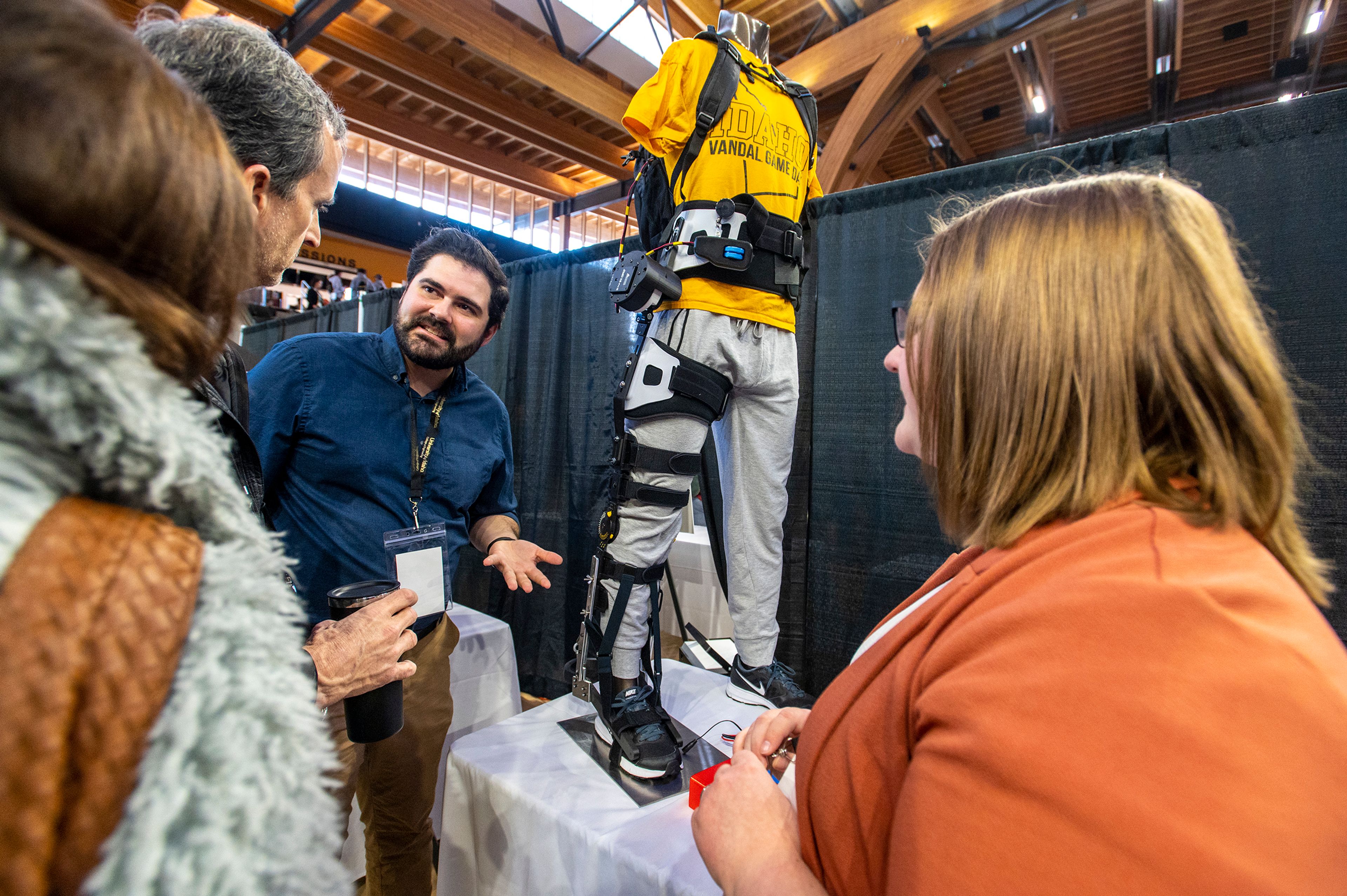 Zach Wilkinson/Daily News Parker Daniel, center, and Rachel Stanley, right, explain the functions of their exoskeleton for multiple sclerosis walking assistance Friday during the University of Idaho College of Engineering’s annual Engineering Design Expo in the Idaho Central Credit Union Arena in Moscow.