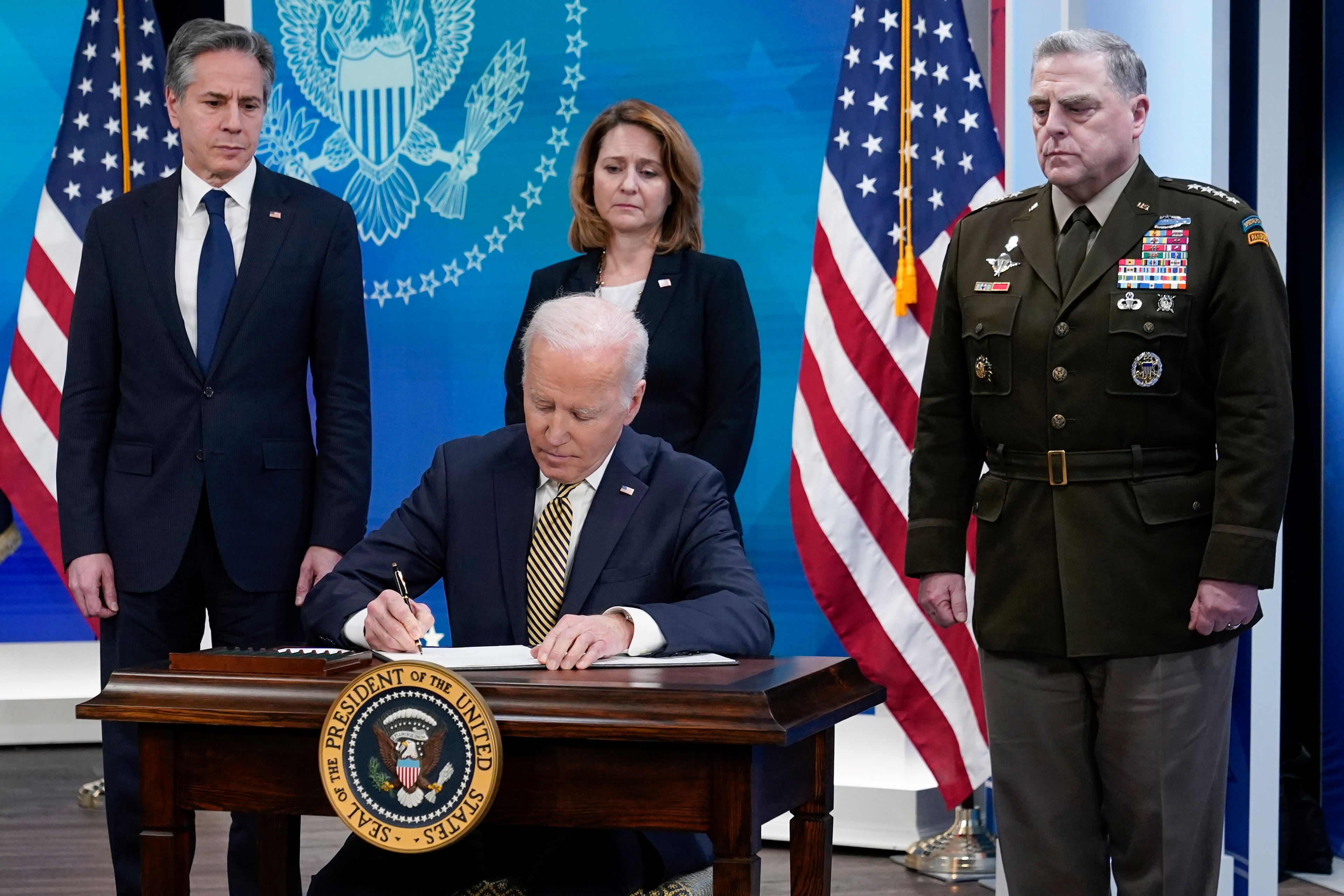 President Joe Biden signs a delegation of authority in the South Court Auditorium on the White House campus in Washington, Wednesday, March 16, 2022. From left, Secretary of State Antony Blinken, Biden, Deputy Secretary of Defense Kathleen Hicks and Chairman of the Joint Chiefs of Staff General Mark Milley. (AP Photo/Patrick Semansky)