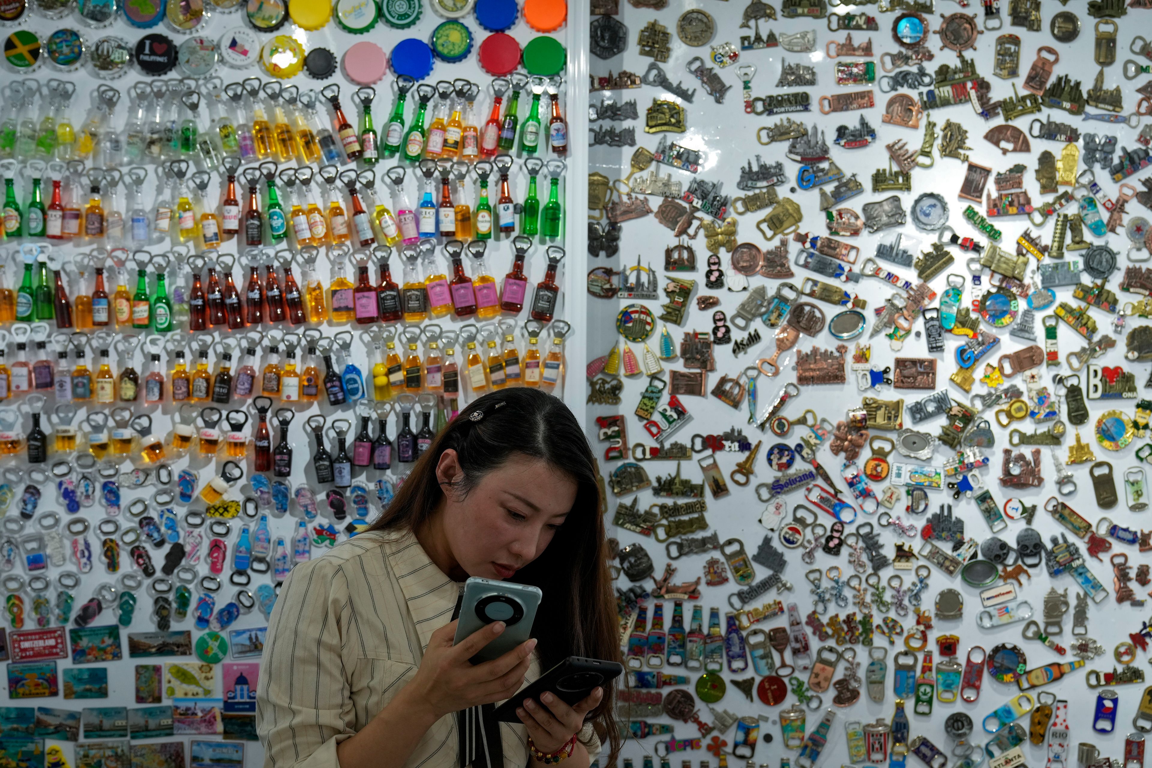 Du Jing stands by variety fridge magnets displayed at her store in the Yiwu wholesale market in Yiwu, east China's Zhejiang province on Nov. 8, 2024. (AP Photo/Andy Wong)