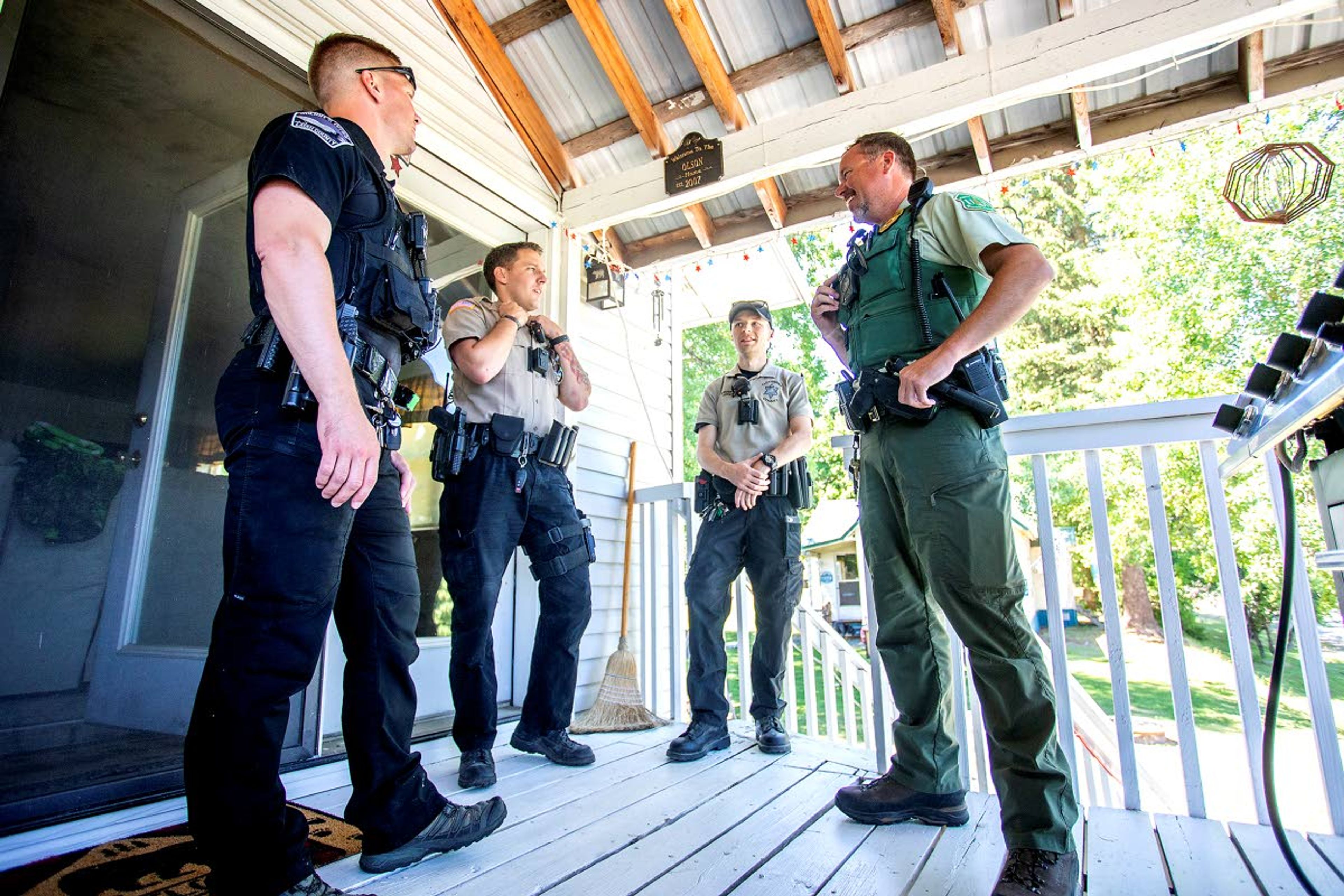 Patrol Deputy Justin Olson (from left), with Latah County Sheriff, Dep. Kasey Light, Dep. Connor McCullough and Steve Bryant, a law enforcement officer with the U.S. Forest Service, chat on the front deck of Diana and Dave Olson's home in Elk River on Saturday. ,