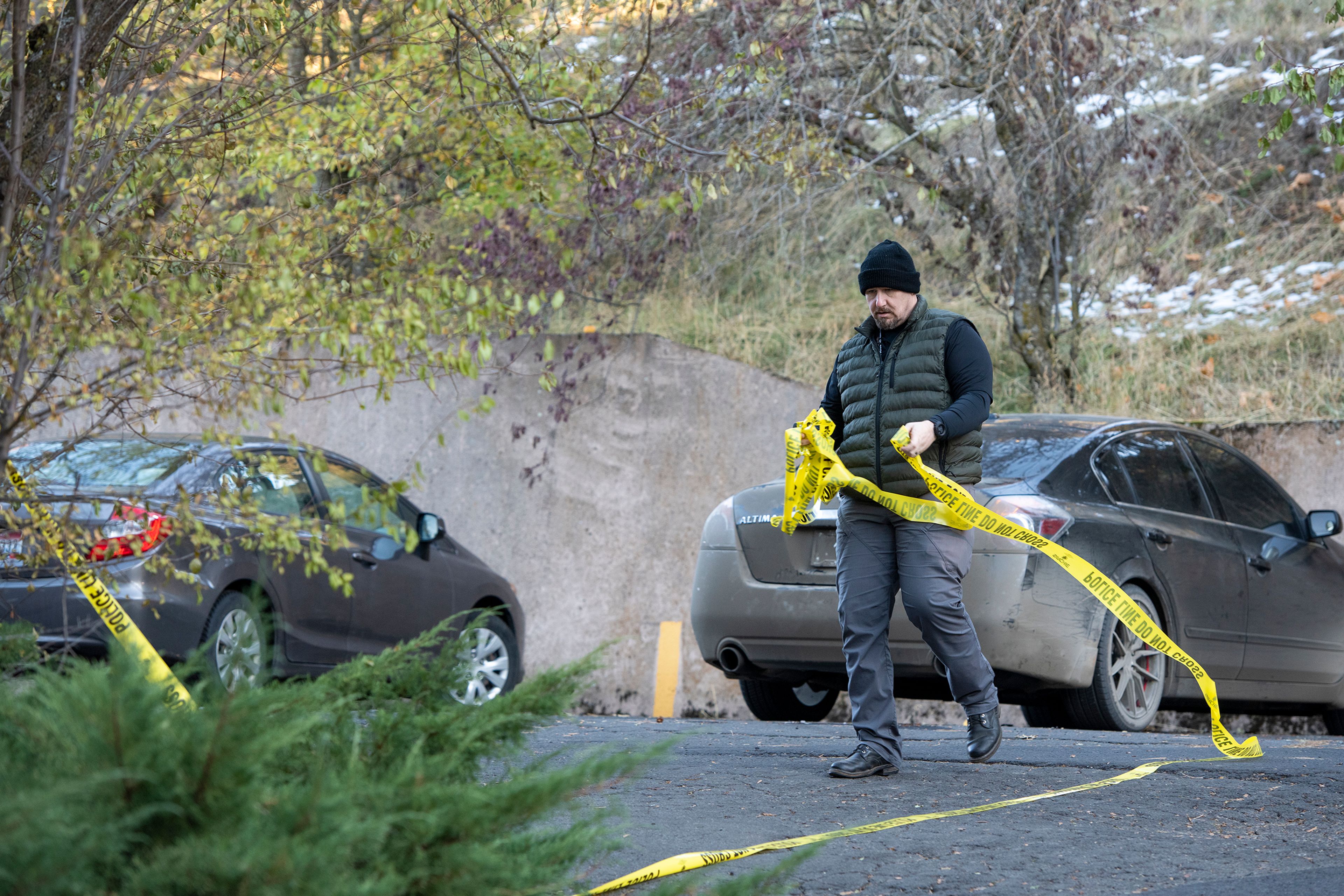 An officer removes caution tape Monday from a parking lot behind the home where four University of Idaho students were stabbed in a quadruple homicide on King Road in Moscow.