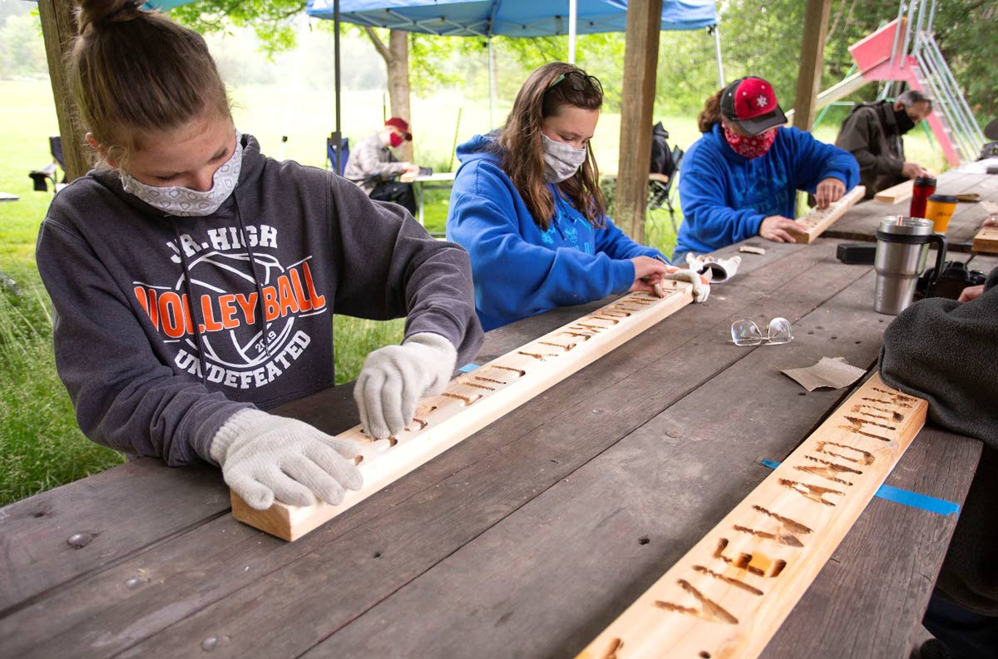 Photos by Geoff Crimmins/Daily NewsVolunteers Olivia Tyler and Eva Bosshardt sand signs before staining them on Saturday at Robinson Park, east of Moscow. Aila Carr-Chellman will install the signs at Idler’s Rest Nature Preserve for her Eagle Scout project.