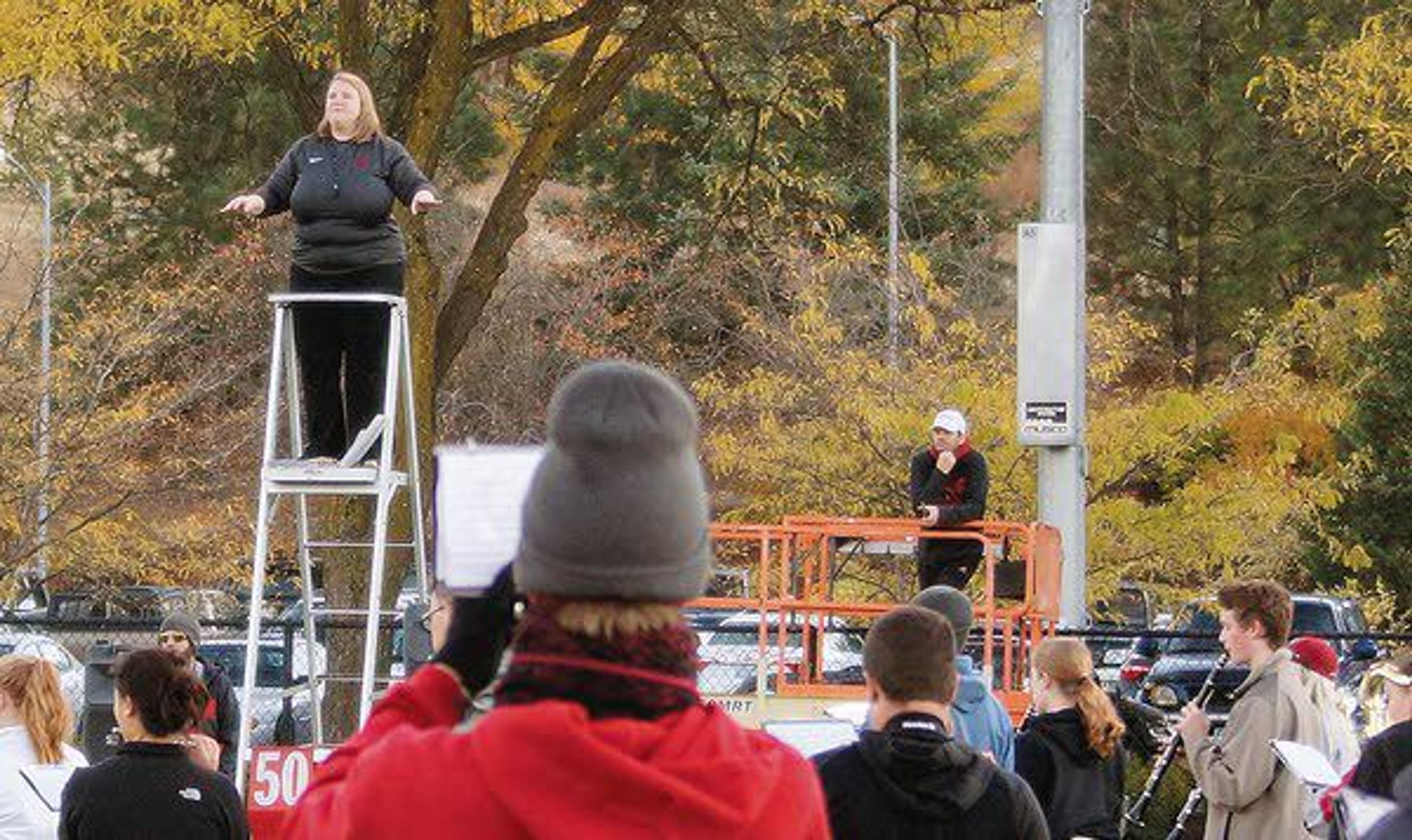 Washington State University Marching Band assistant director Sarah Miller conducts a rehearsal from a director's tower October 24 as fellow assistant director Brent Edwards, in white hat, listens.