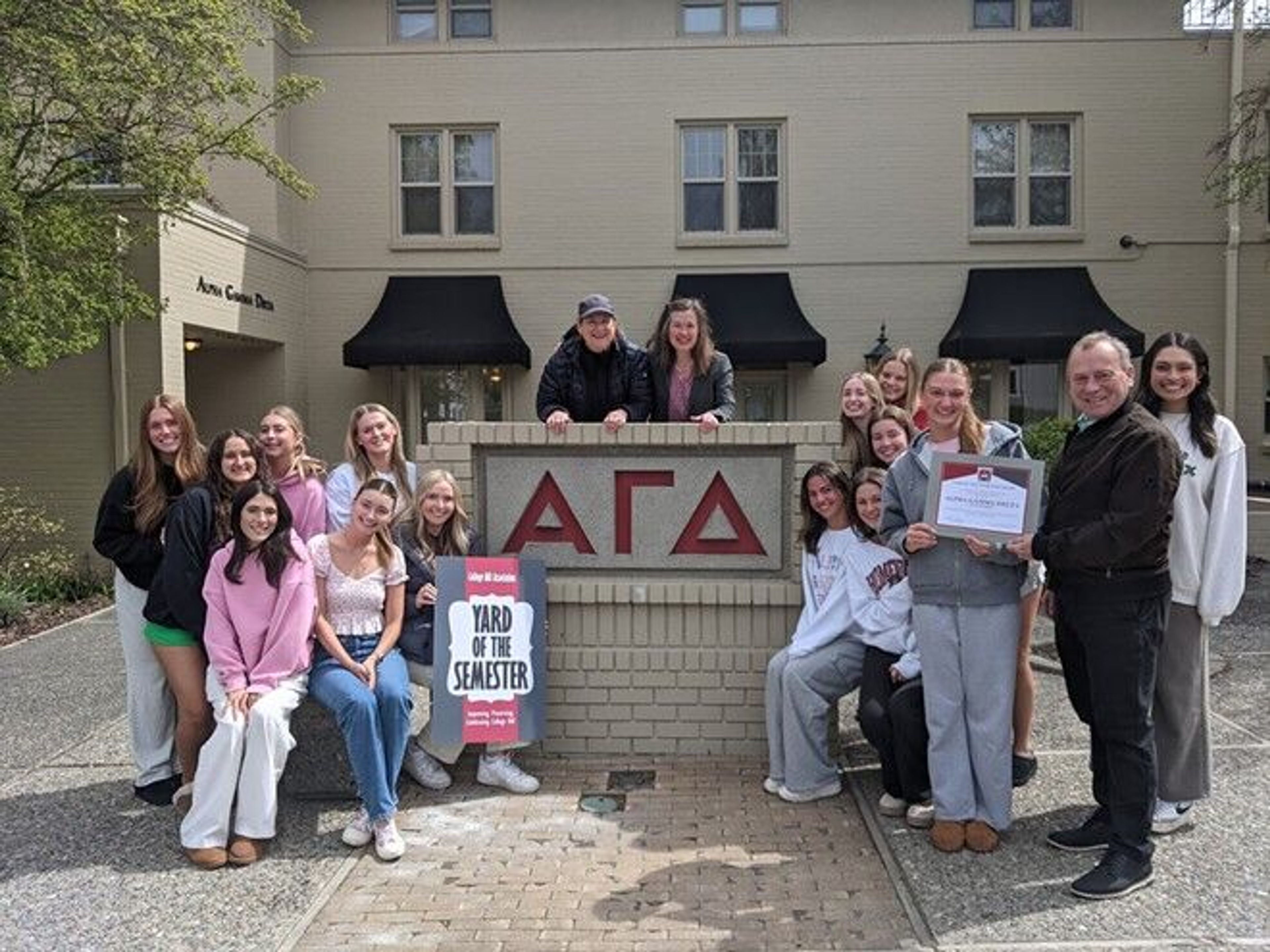 Alpha Gamma Delta residents rally for the chapter's recognition as Sorority Yard of the Semester on April 21. Pullman Mayor Francis Benjamin presents the award certificate to Philanthropy Chair Camden Anderson, while House Director Monica Anderson and College Hill Association Co-Chair Allison Munch-Rotolo look on from behind the sign. Ms. Anderson oversees maintenance of the property at 900 NE B Street in Pullman and says it is the "Best job ever!"