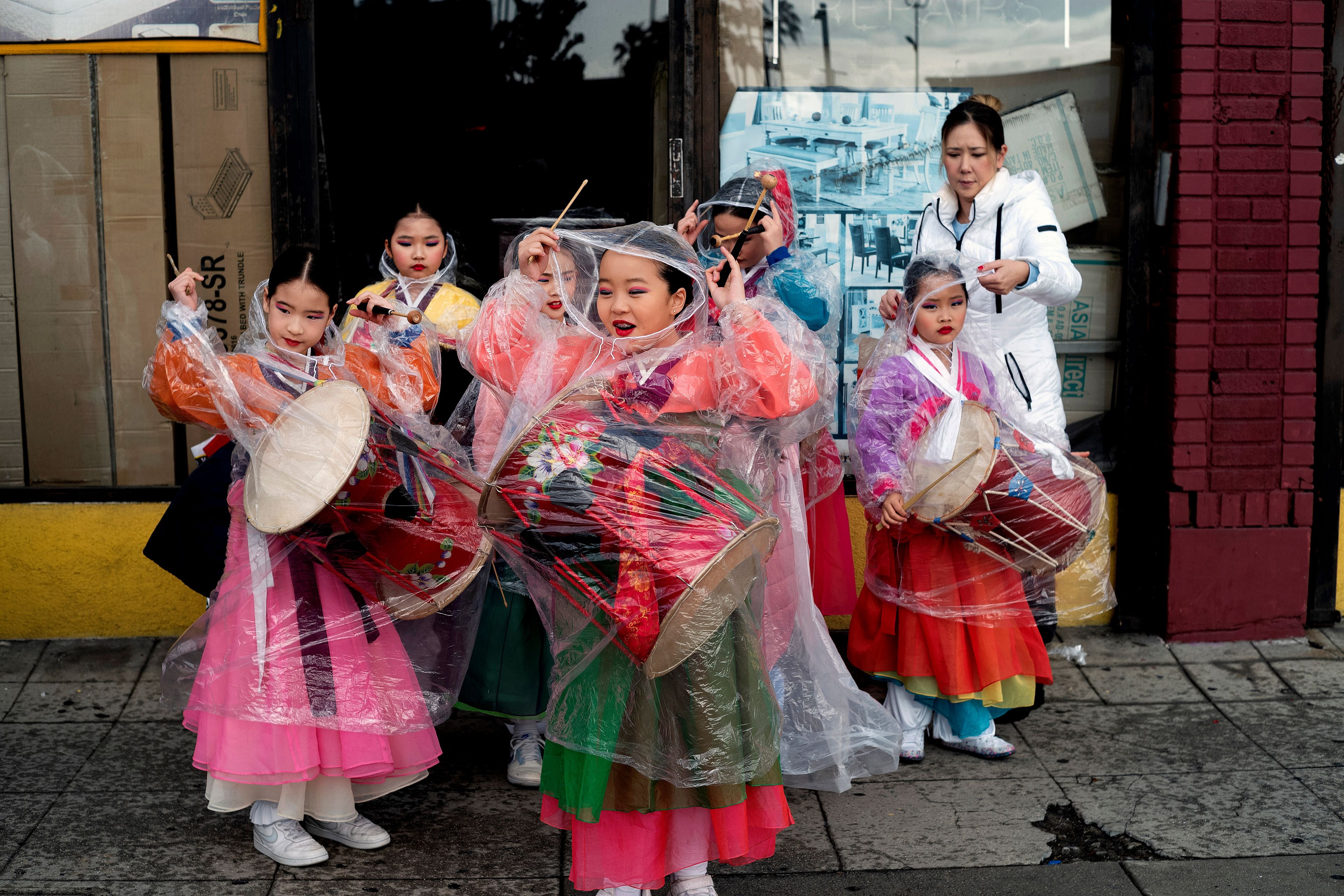 The Kim Eung Hwa Korean Dance Academy students put on protective rain coats prior to participating in the Kingdom Day Parade in Los Angeles on Monday, Jan. 16, 2023. After a two-year hiatus because of the COVID-19 pandemic, the parade, America's largest Martin Luther King Day celebration returned. (AP Photo/Richard Vogel)