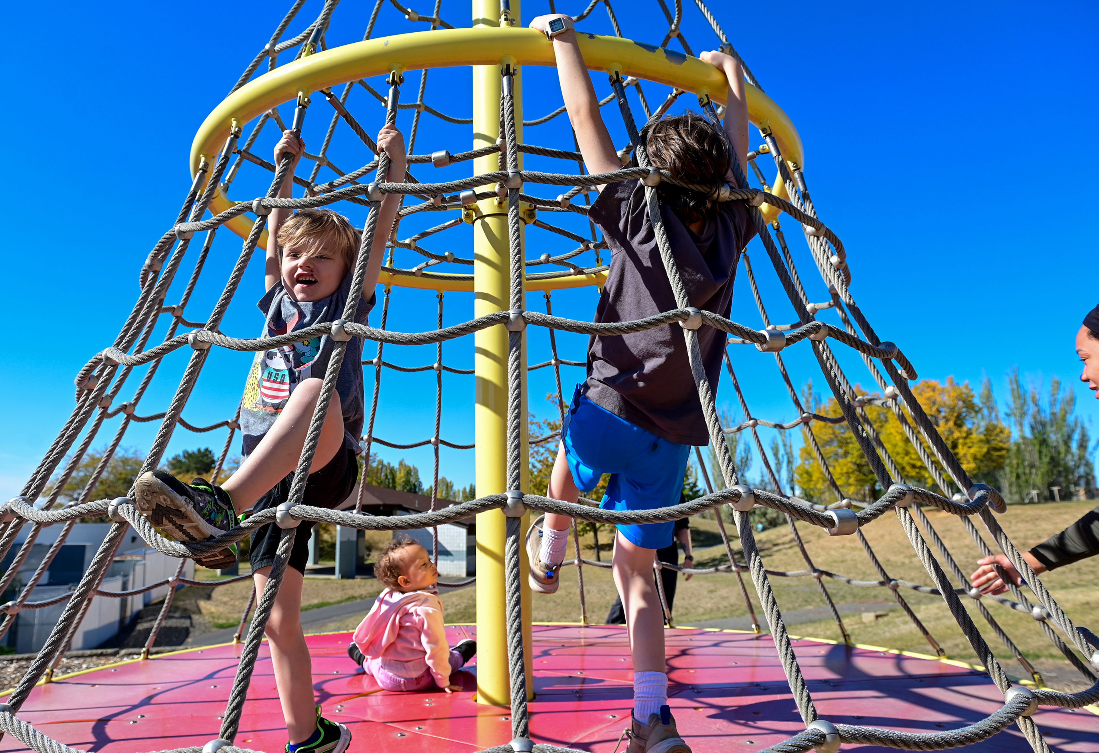 From left: Radly, 4, Faye, 1, and Oz, 10, are spun by Tasha Baker, right, as they play Thursday at Military Hill Park in Pullman.