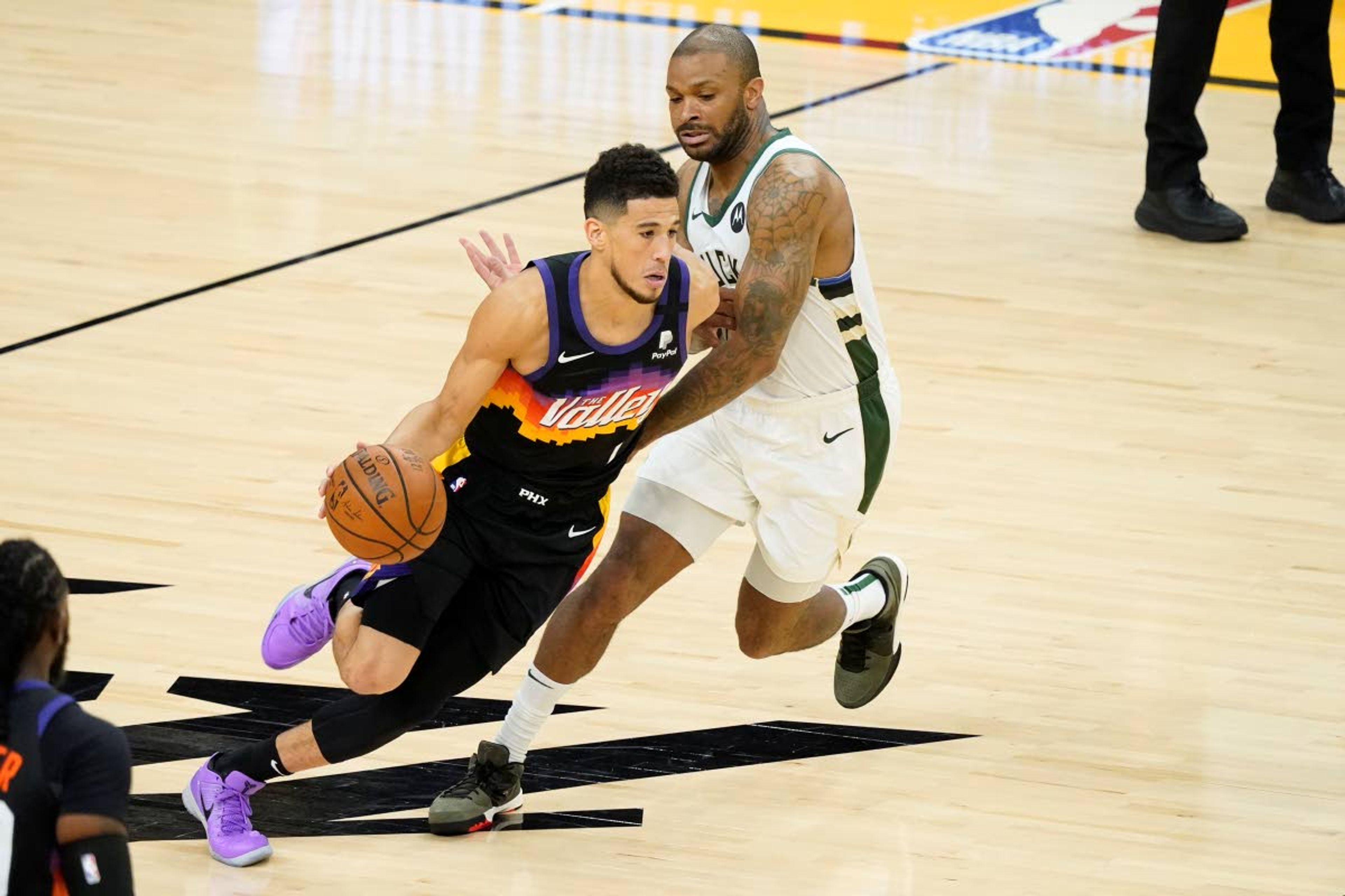 Phoenix Suns guard Devin Booker, left, dribbles against Milwaukee Bucks forward P.J. Tucker during the first half of Game 2 of basketball's NBA Finals, Thursday, July 8, 2021, in Phoenix. (AP Photo/Matt York)