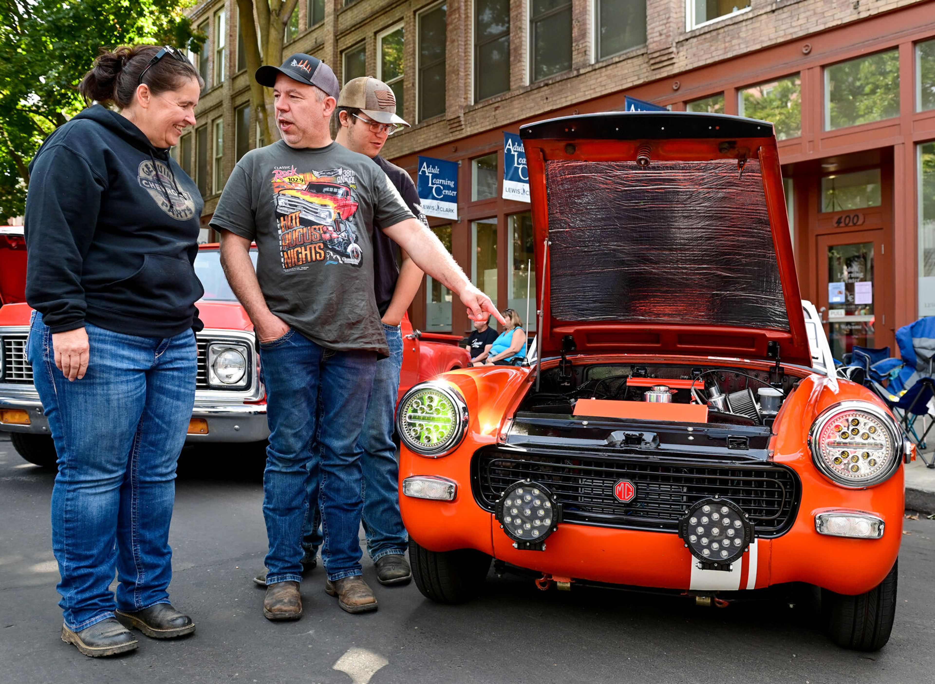 Amie, from left, Jay and Evan Scheinost talk over a 1972 MG Midget on display along Main Street, down the road from their own entry, a 1972 Chevy K10, at the Lewiston Hot August Nights on Saturday in Lewiston.