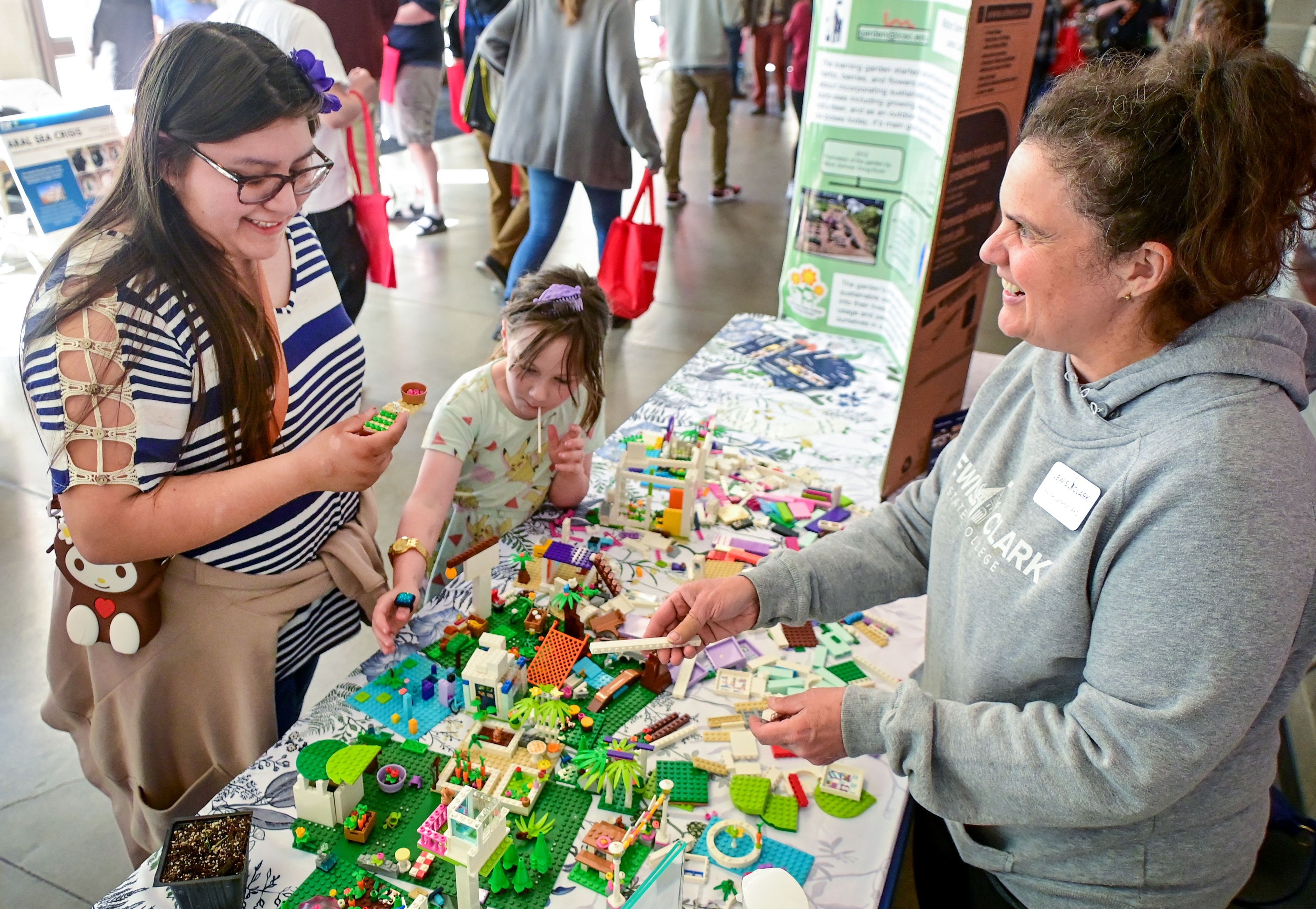 Berenice Lainez-Pintor, left, a junior at Washington State University, and Maven, 7, add to a Lego garden with help from Lewis-Clark State College chemistry professor Rachel Jameton, right, at the Earth Day event in Pullman on Sunday. The booth taught attendees about the evolution of a learning garden in Lewiston.