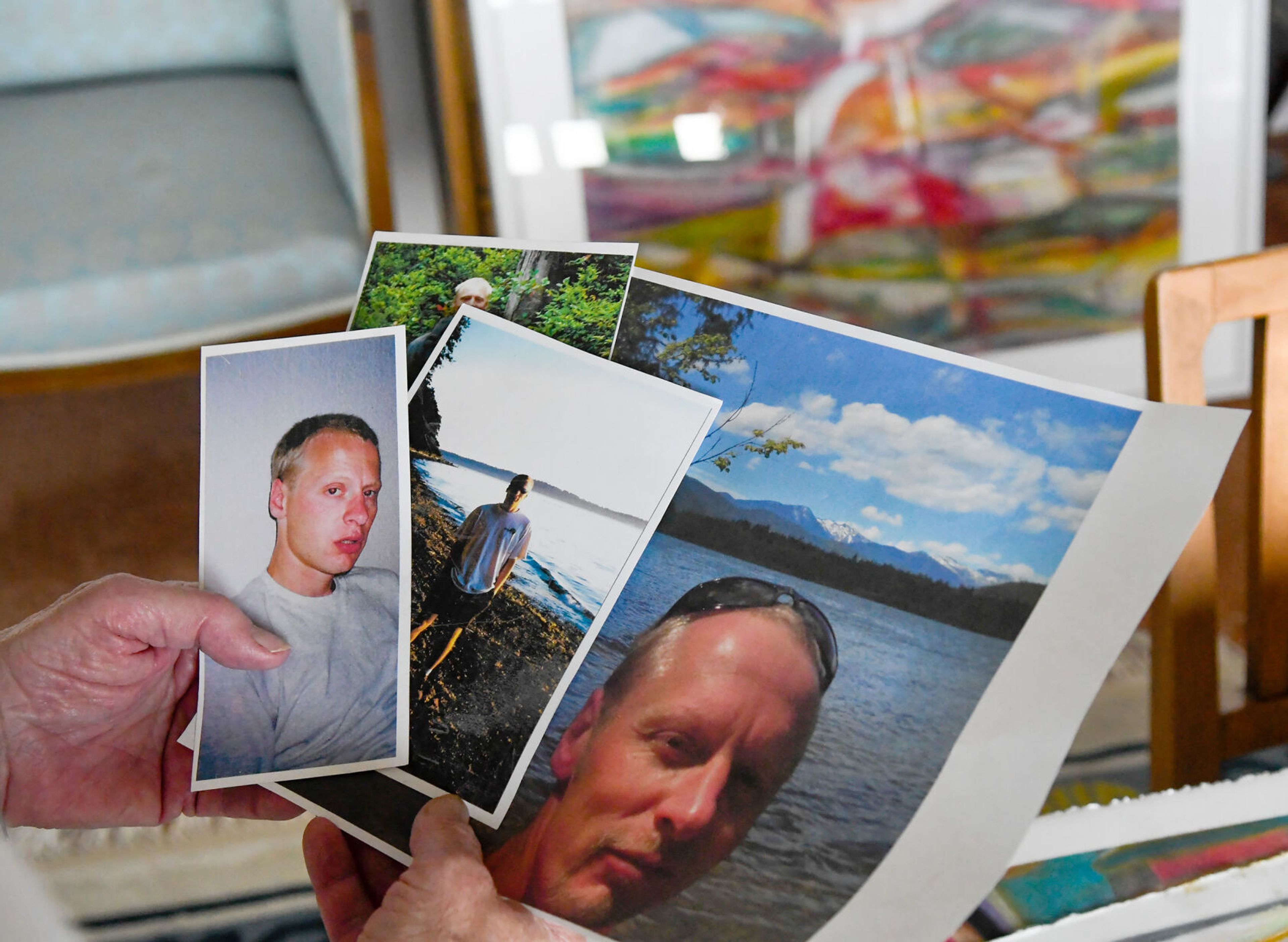 Karen Kiessling holds photos of son Dan Kiessling over a few pieces of Dan’s artwork at their home in Pullman on Tuesday. A collection of Dan’s Palouse County pastels will be shown at a celebration of life art show in his honor on June 22 at the Bank Left Art Gallery in Palouse.