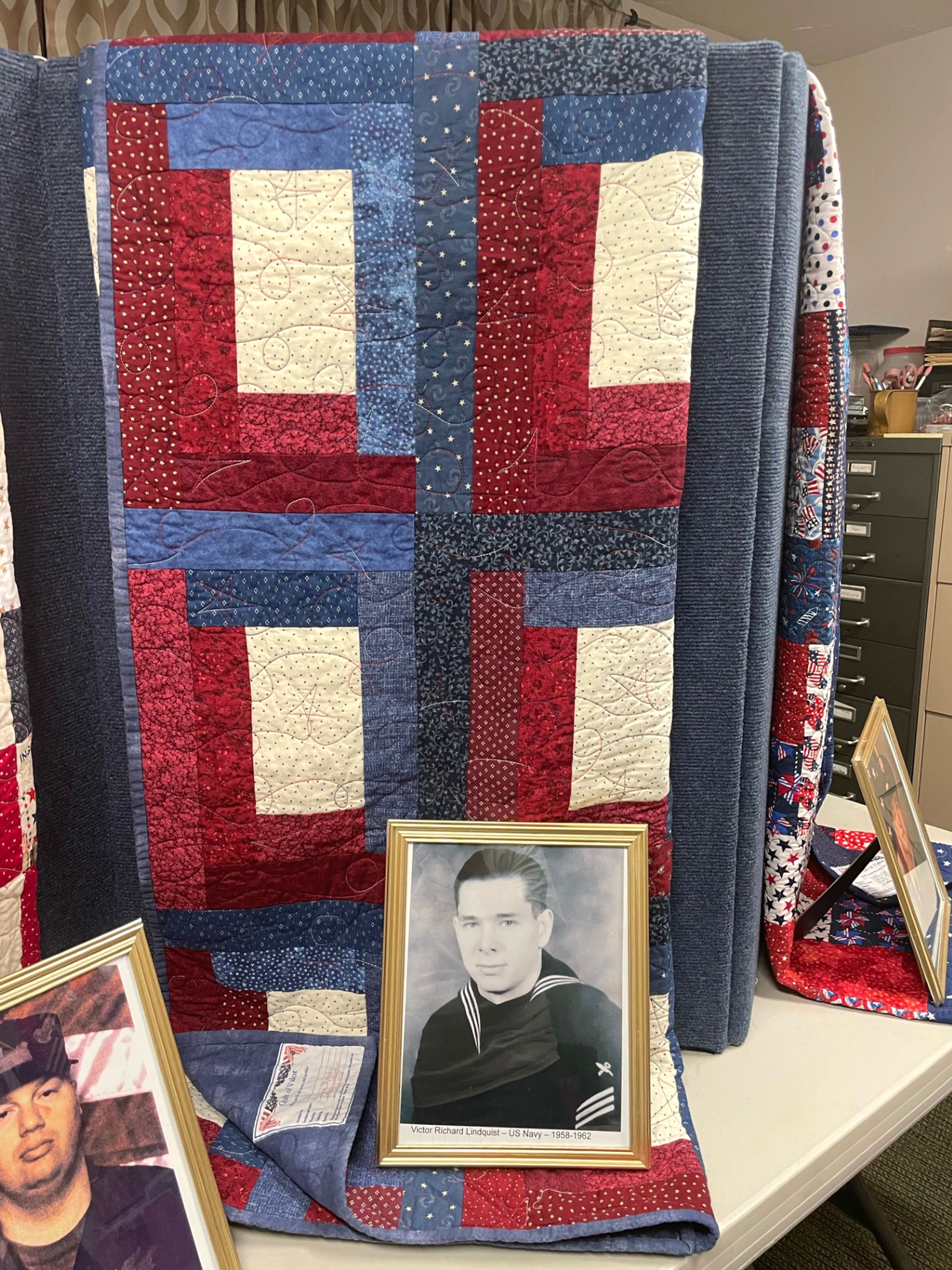 A picture of Victor Lindquist, Navy, sits with his quilt of valor.