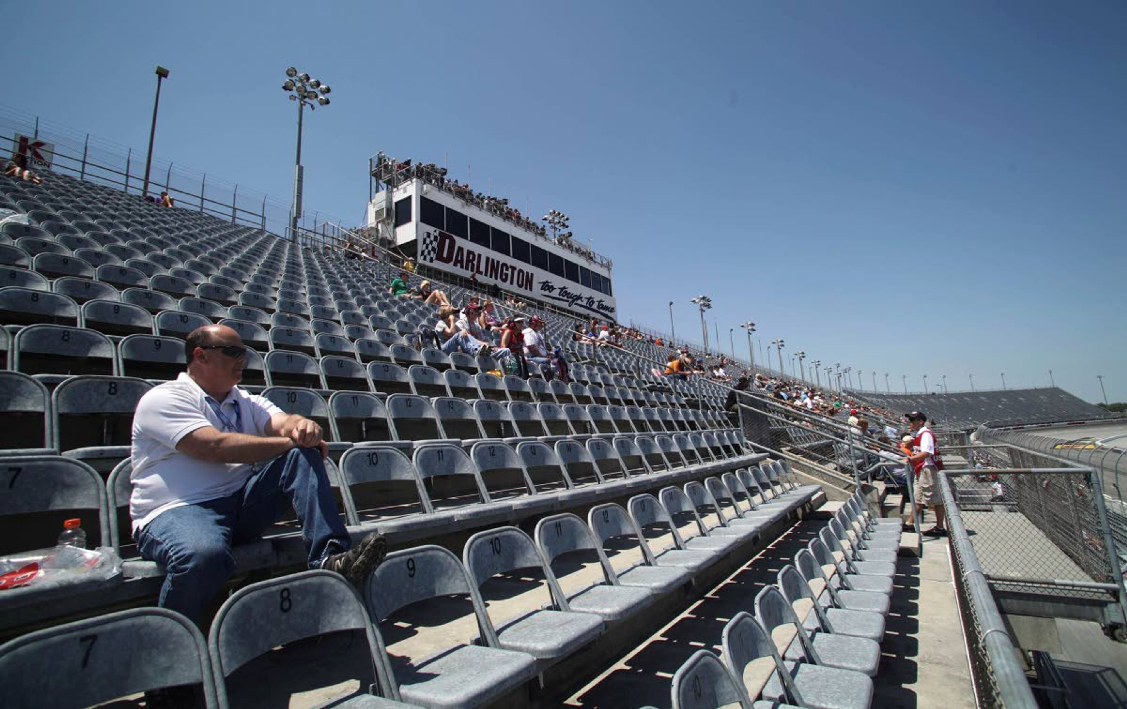 FILE - In this May 11, 2012, file photo, a few fans are shown in the grandstands to watch NASCAR auto racing practice at Darlington Raceway in Darlington, S.C. NASCAR will get its season back on track starting May 17 at Darlington Raceway in South Carolina without spectators, and the premier Cup Series plans to race four times in 10 days at a pair of iconic tracks. The revised schedule released Thursday, April 30, 2020, goes only through May and has a pair of Wednesday races — fulfilling fans longtime plea for midweek events. (AP Photo/Willis Glassgow, File)