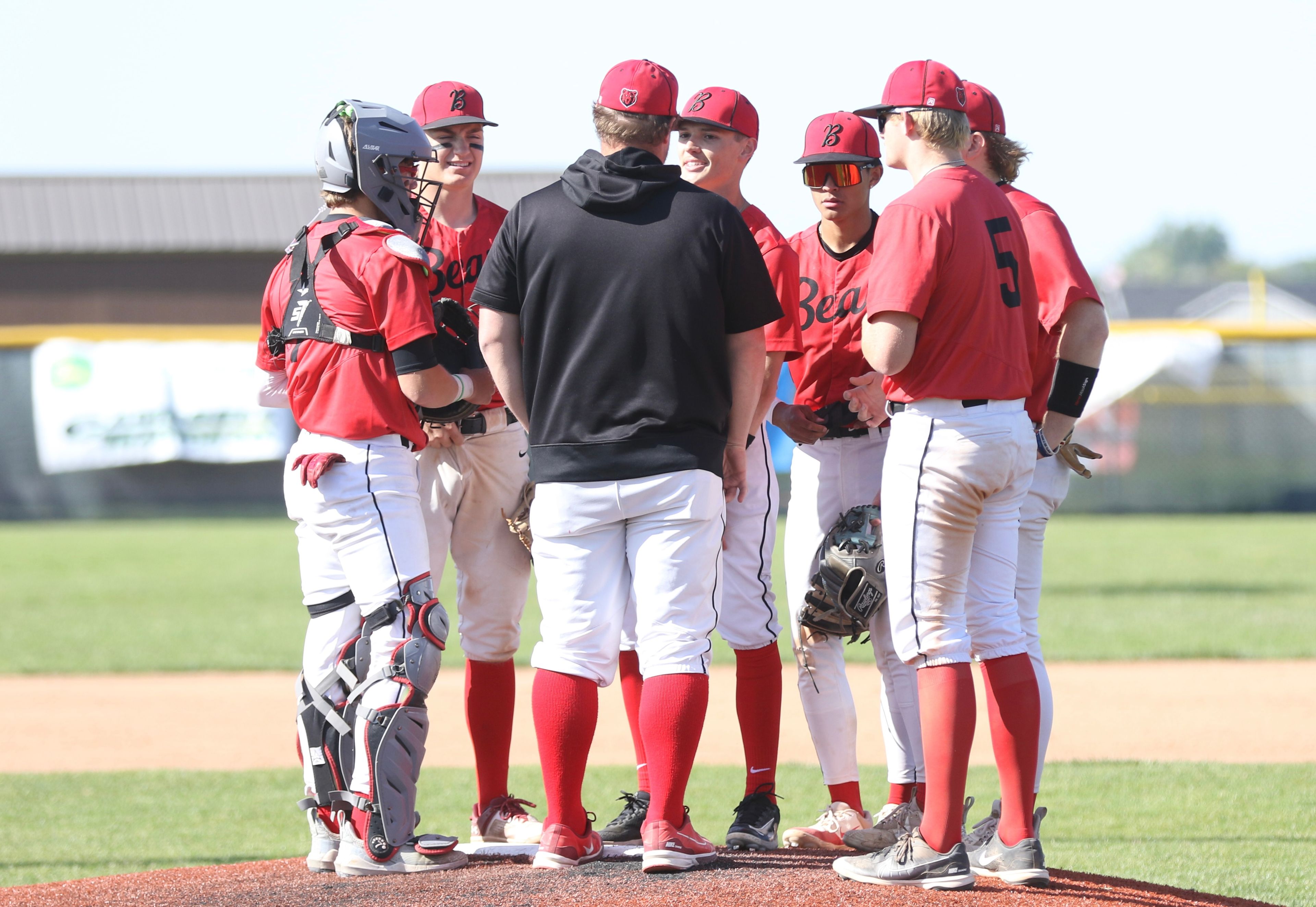 Moscow pitching coach Matt Larkin (front center) and the Moscow infield visit with pitcher Butch Kiblen (back center) during an Idaho Class 4A state tournament game against Blackfoot at Vallivue High School in Caldwell, Idaho.