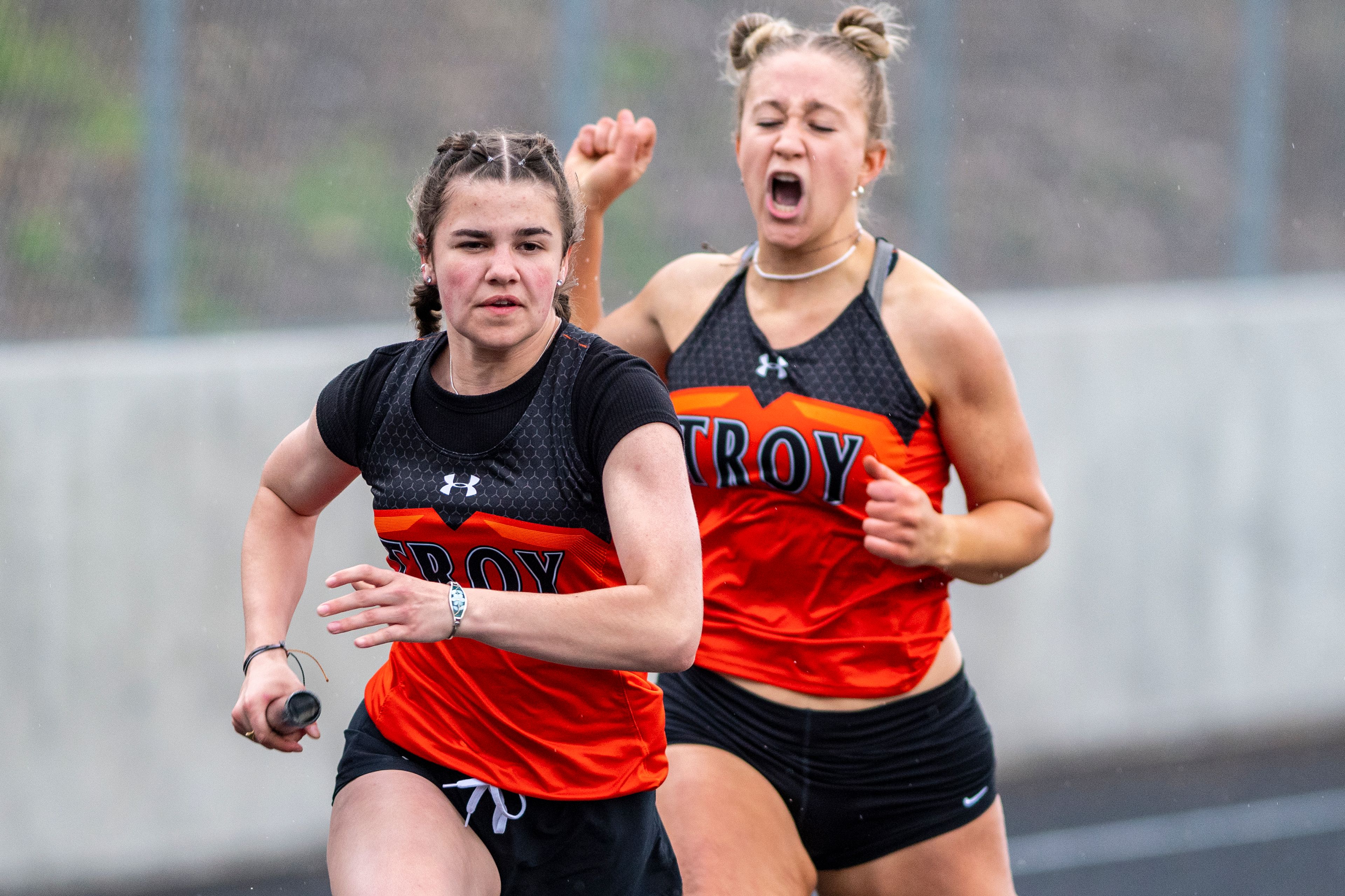 Troy High senior Morgan Blazzard, right, yells words of encouragement after passing the baton to sophomore Bethany Phillis in the girls 400 meter relay Thursday at the District II Meet of Champions.