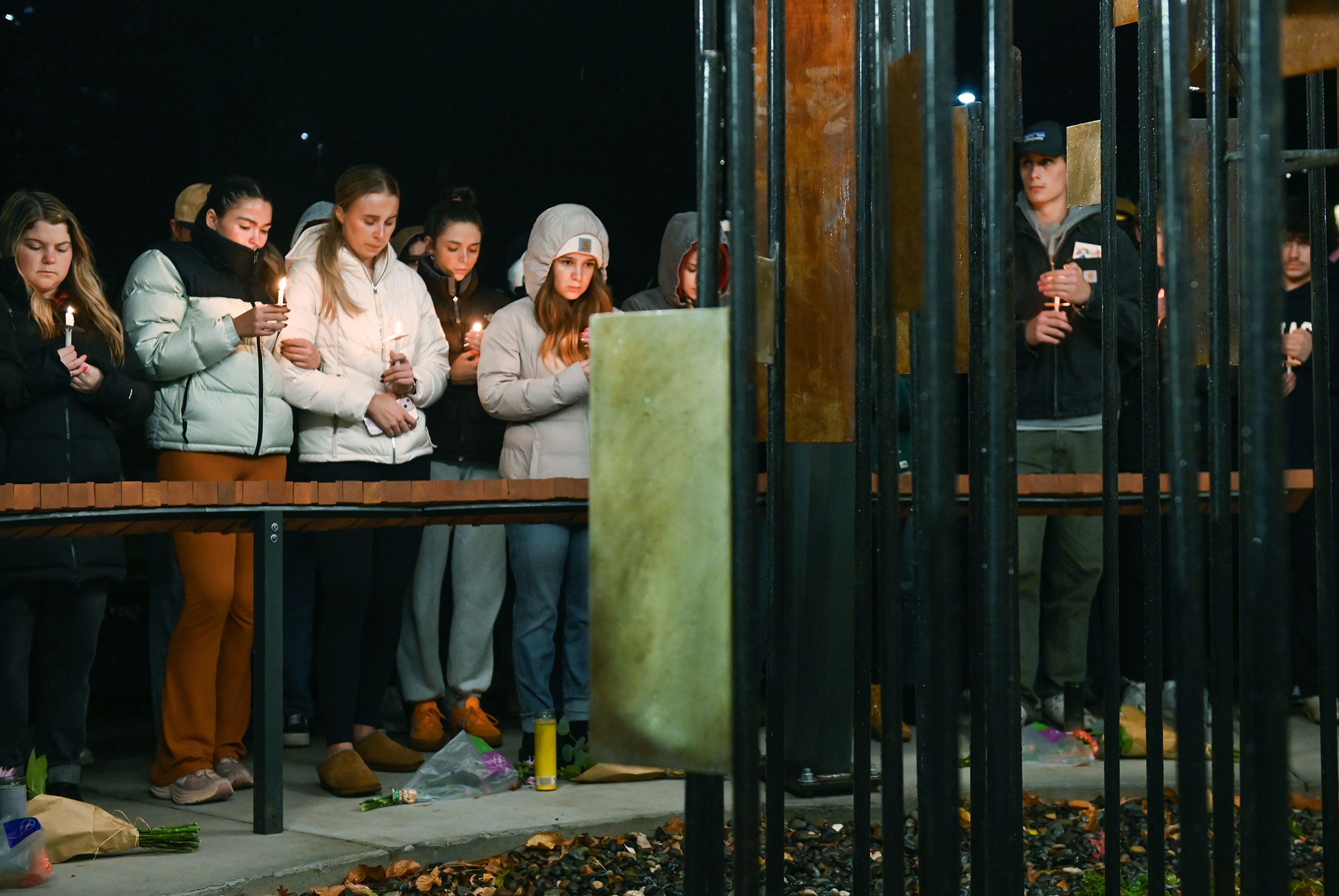 Those gathered for a vigil marking two years since the murder of four University of Idaho students stand in front of their names and the sculpture dedicated to the four lost at the Vandal Healing Garden and Memorial Wednesday in Moscow.