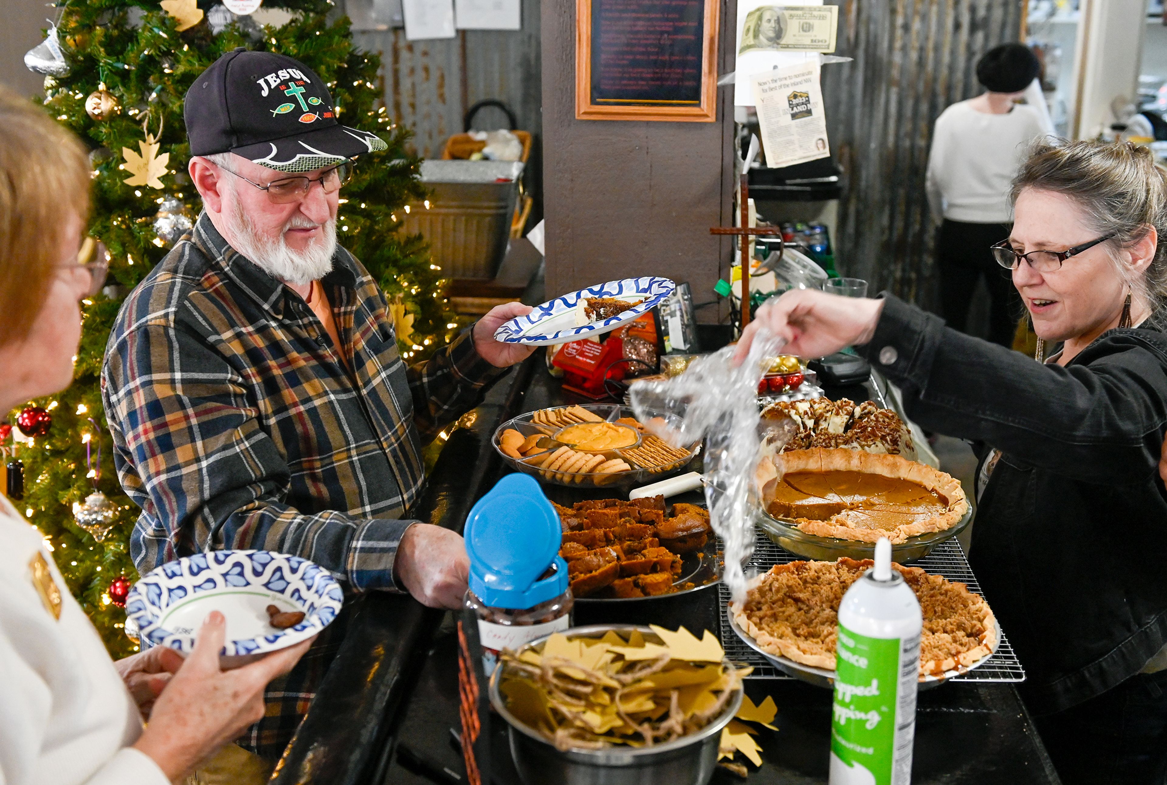 Anita LaPlante, left, and Mark Byrd, center, line up for dessert at the bar of Waha Grill as co-owner Wendy Hayward, right, unwraps treats during the restaurant’s annual free Thanksgiving meal on the outskirts of Lewiston.