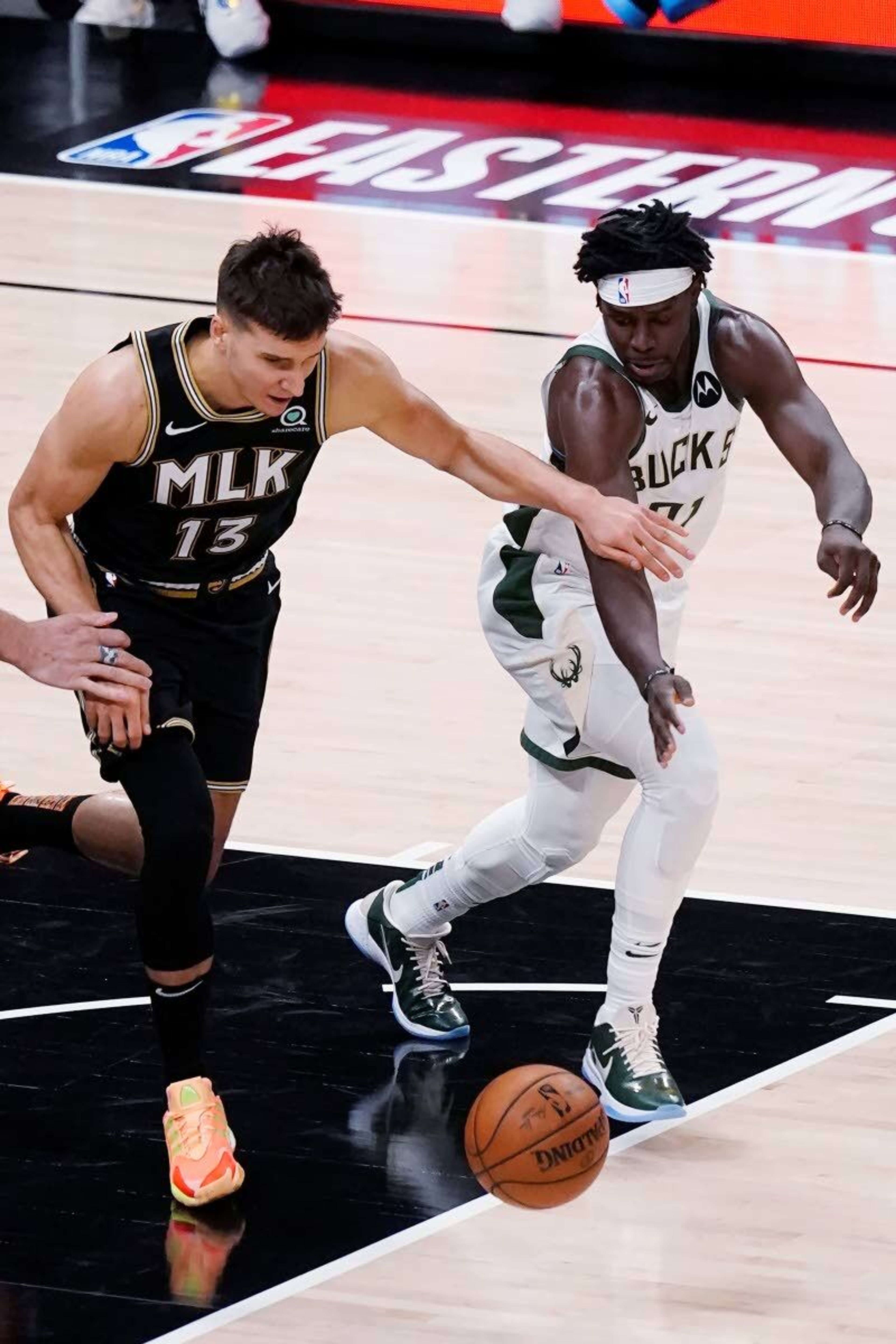 Milwaukee Bucks guard Jrue Holiday (21) steals the ball from Atlanta Hawks guard Bogdan Bogdanovic (13) during the first half pf Game 6 of the Eastern Conference finals in the NBA basketball playoffs Saturday, July 3, 2021, in Atlanta. (AP Photo/John Bazemore)