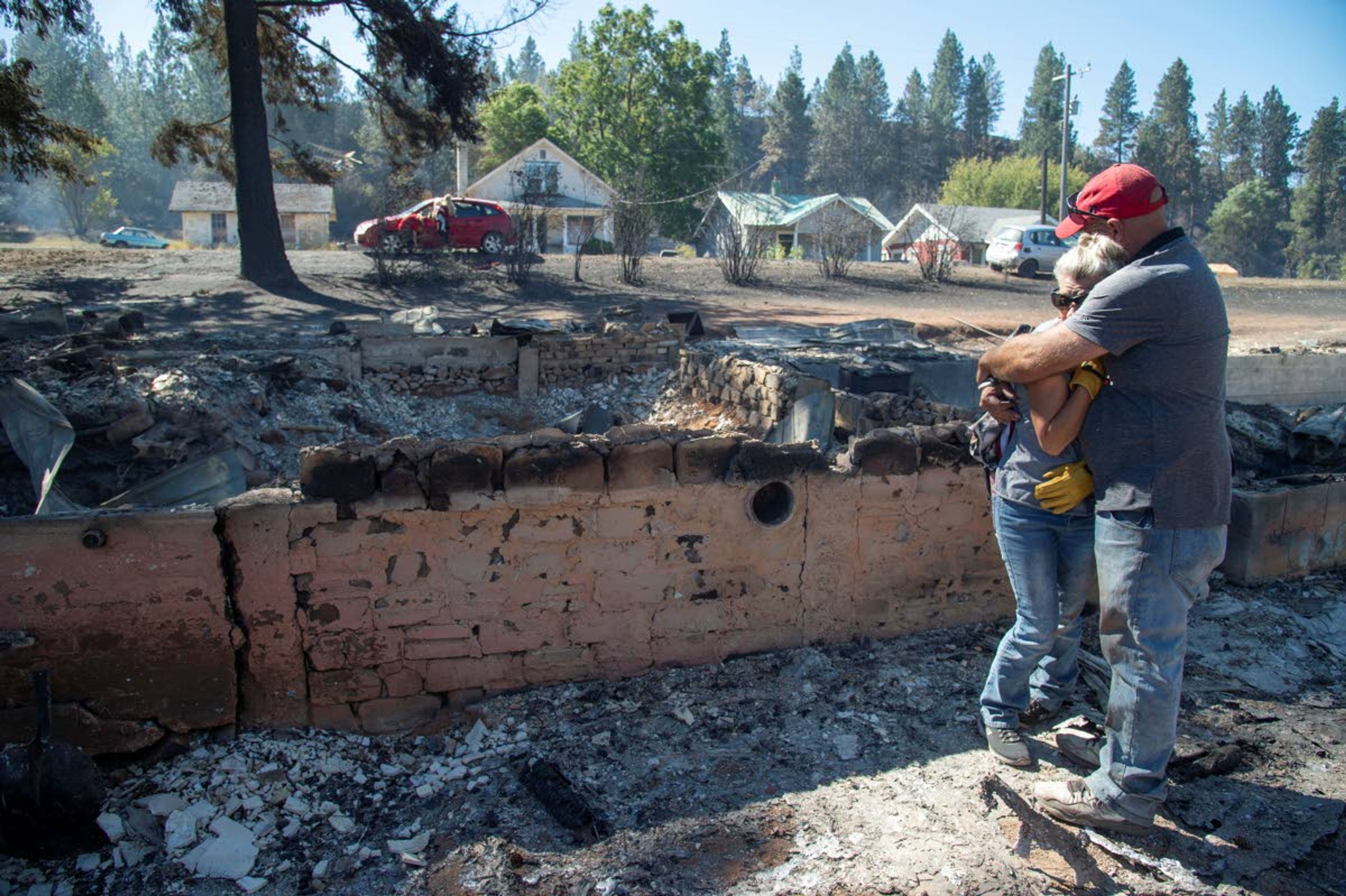 Shawn Thornton hugs his wife, Shannon Thornton, next to the rubble of their burned home Tuesday in Malden, Wash., the day after a fast-moving wildfire swept through the town. Shawn and Shannon weren’t home at the time, but their son, Cody, was and managed to get their dog and a few belongings before leaving just minutes before the flames swept through.