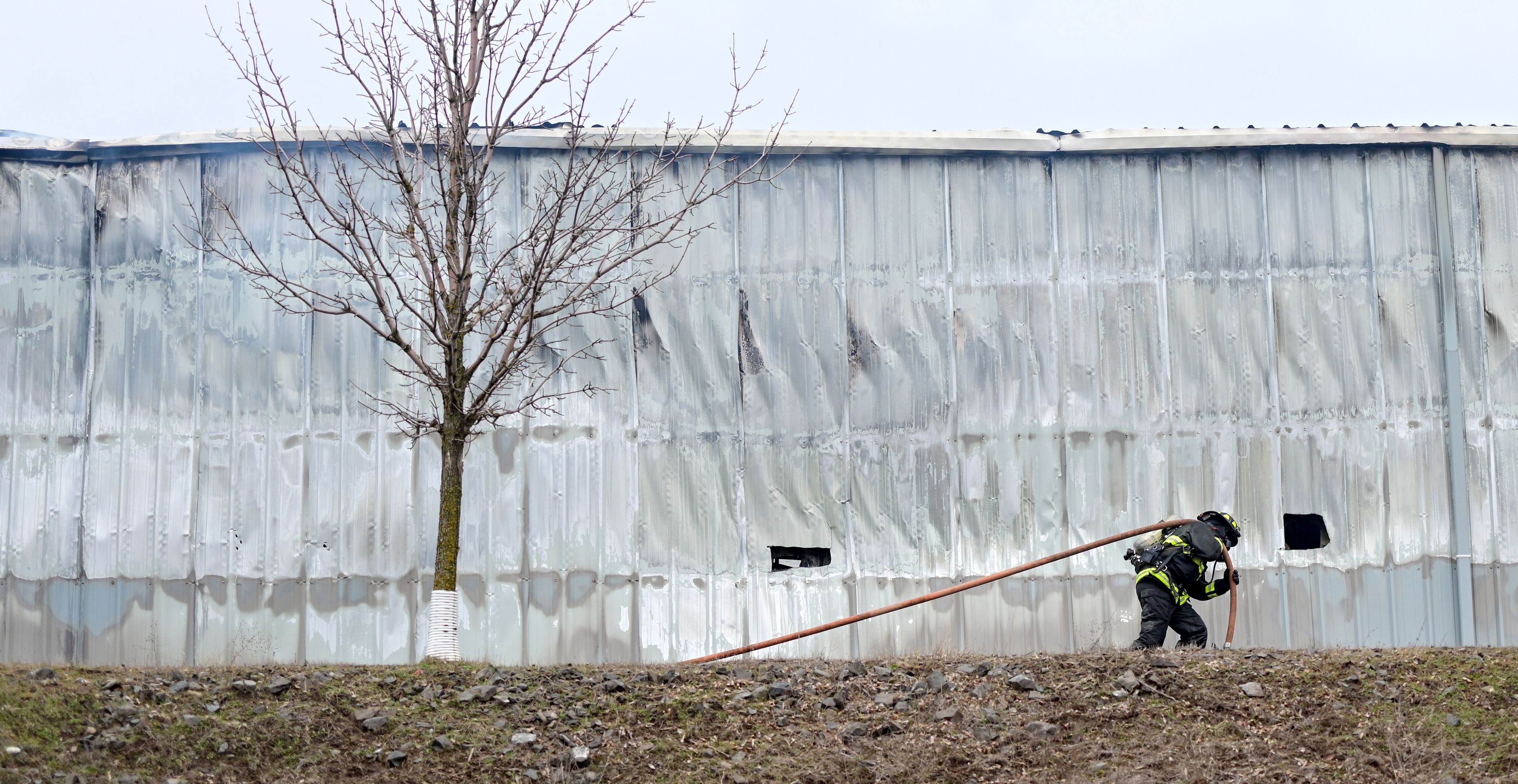 A hose is carried along the side of Express Storage in the aftermath of the large fire along Moscow-Pullman Highway on Thursday.