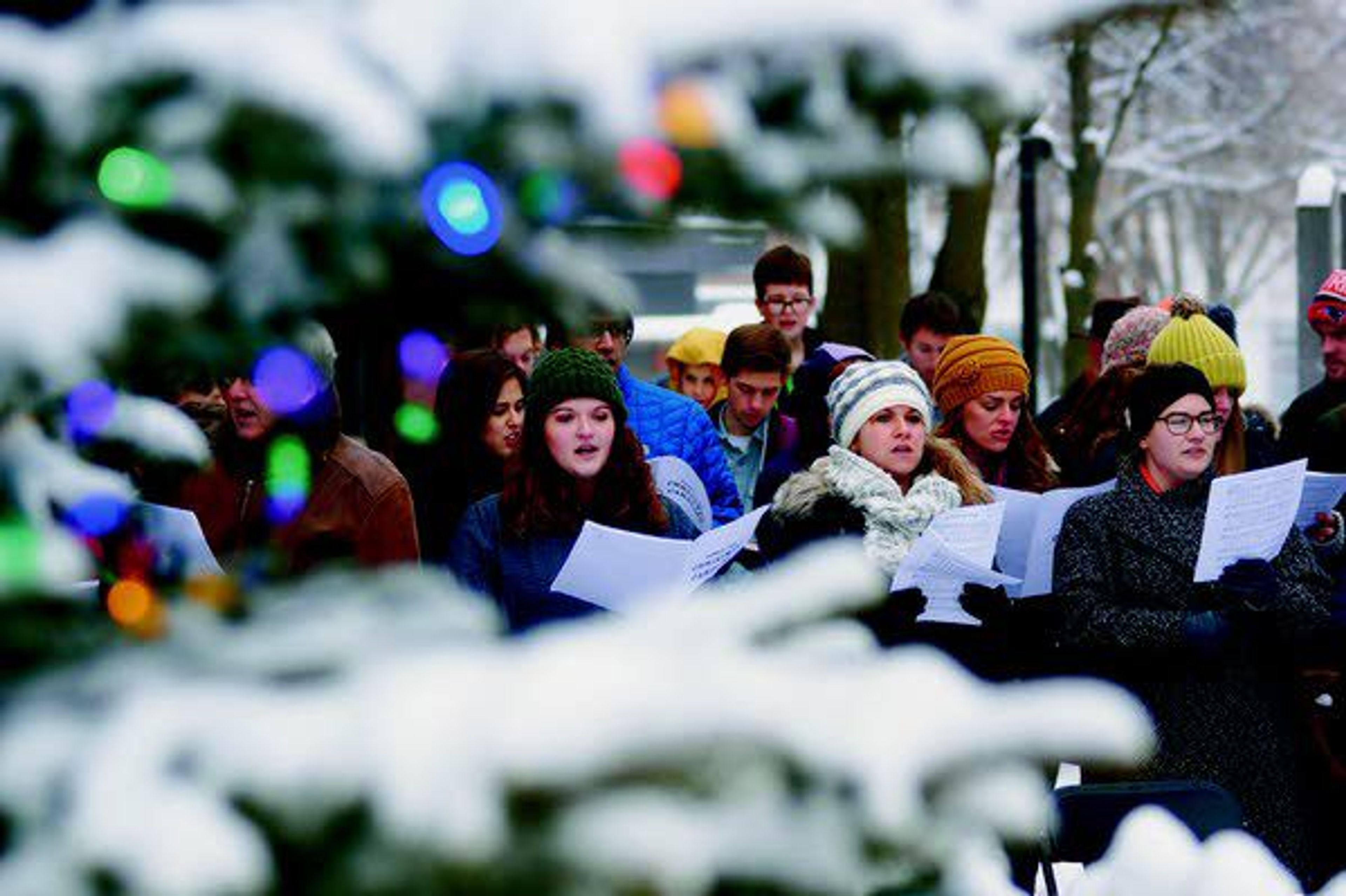 Framed by the branches of a Christmas tree Saturday, carolers sing at Friendship Square in Moscow.