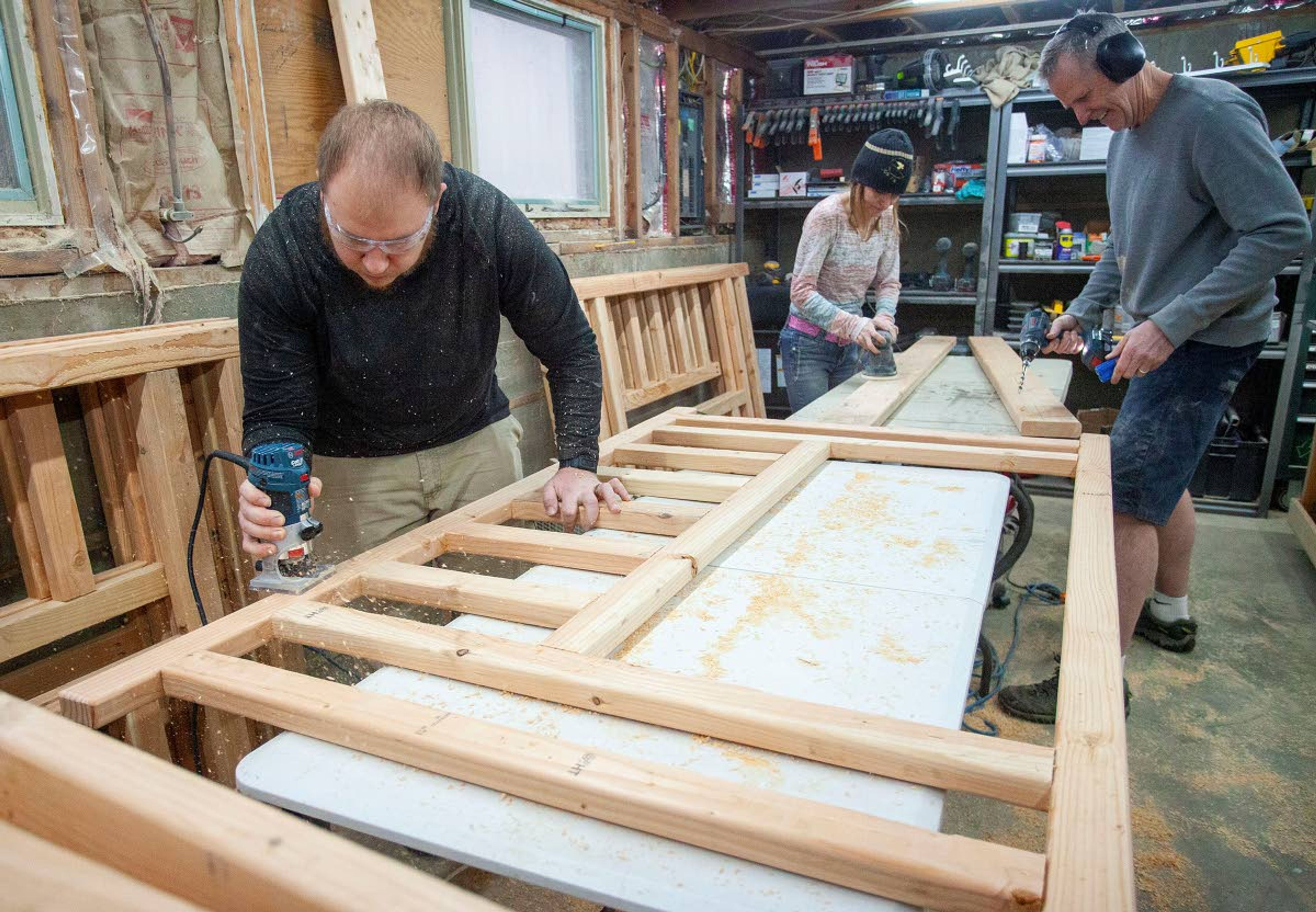 Volunteers Zachary Reid of Pullman, left to right, Misty Zornacki of Endicott and Tim Ball of Coeur d’Alene build bunk beds Feb. 7 at Thad DeBuhr’s home in Pullman. The beds are being built through Blessing Beds, which donates beds to local children who would otherwise sleep on the floor.