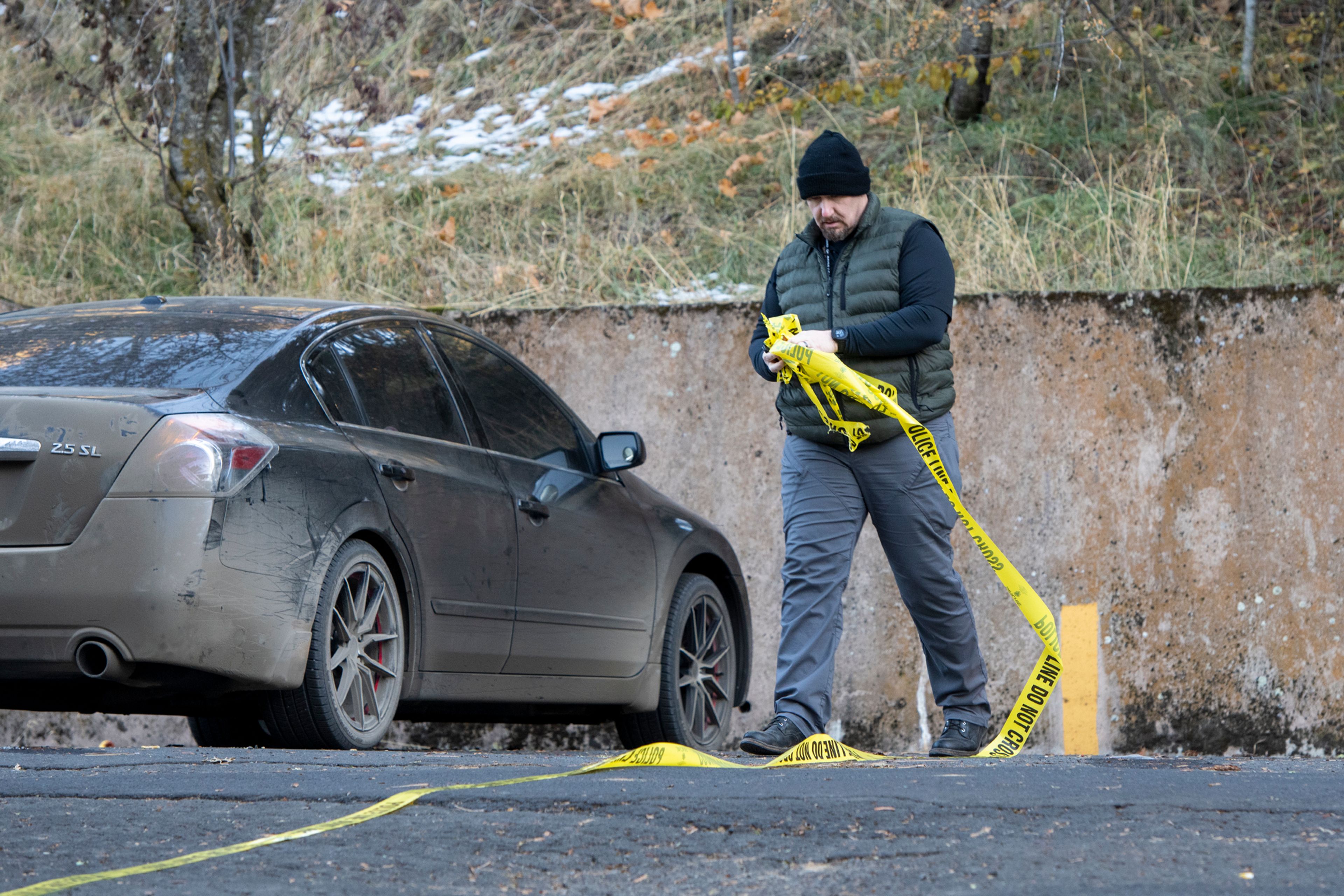 An officer removes caution tape Monday from a parking lot behind the home where four University of Idaho students were stabbed in a quadruple homicide on King Road in Moscow.