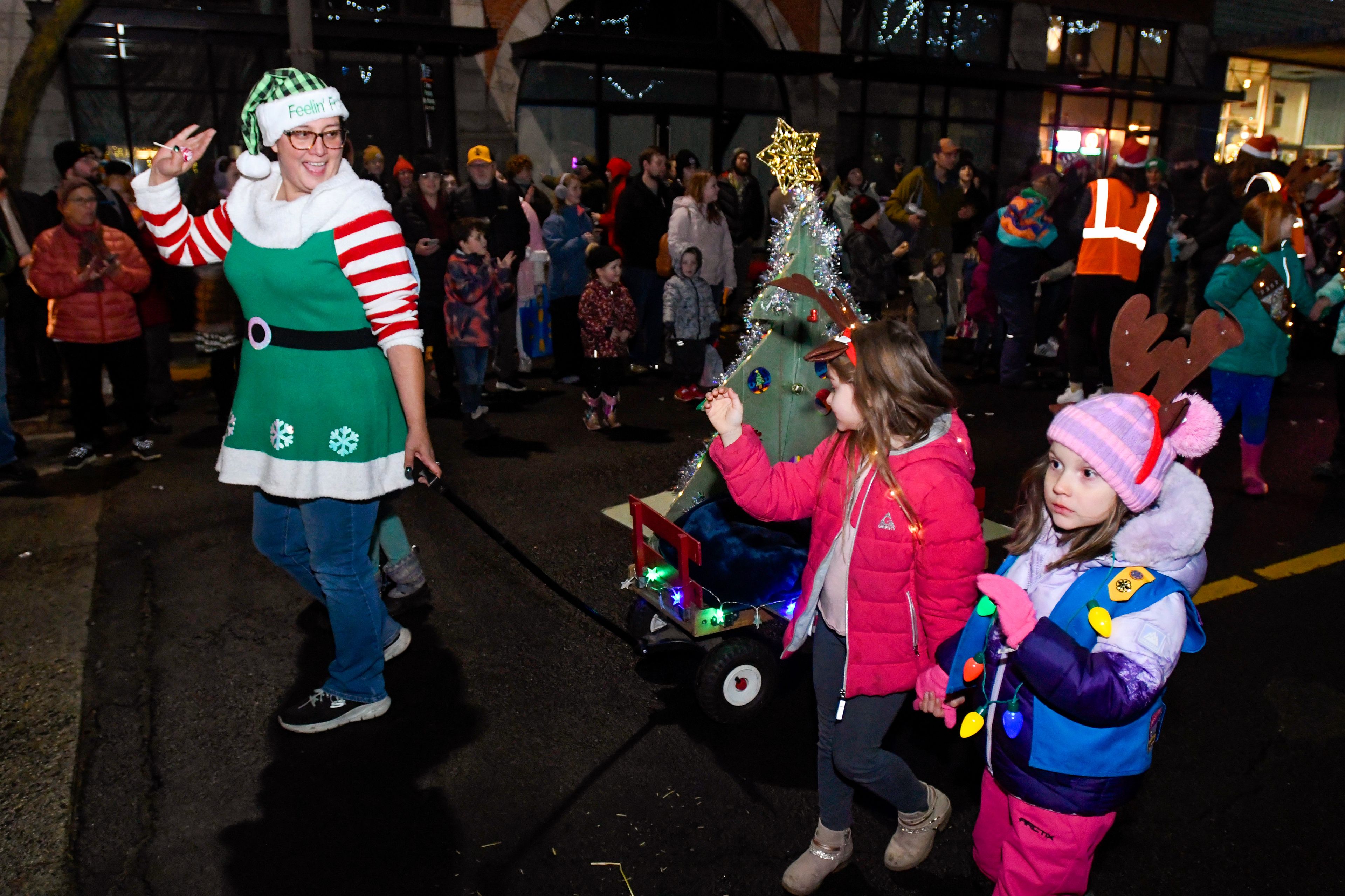 Local Girl Scouts wave to the crowd as they make their way down Main Street in the Light Up the Season parade in Moscow on Thursday.