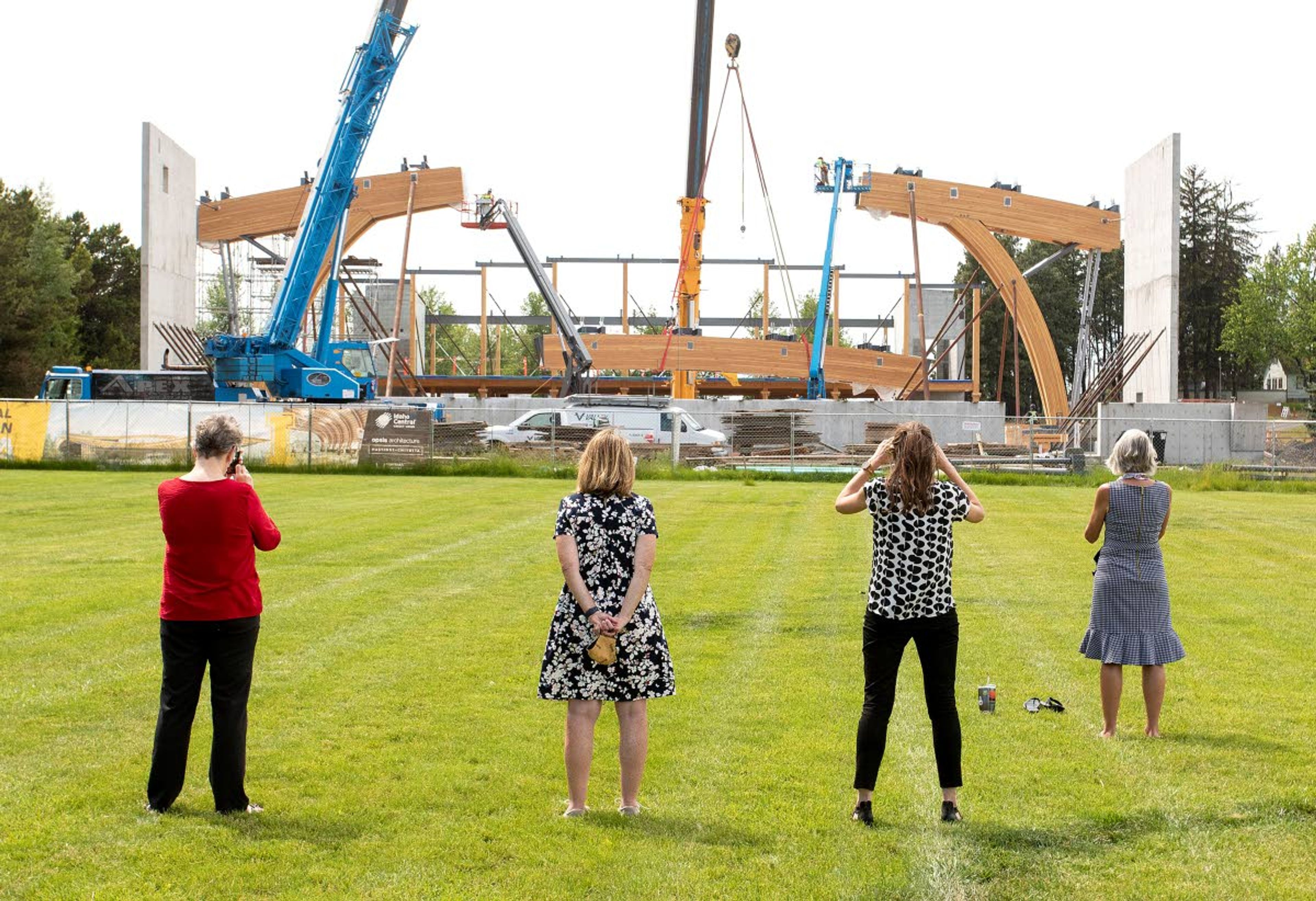 People watch while a laminated wood beam is lifted into place with a crane on Wednesday at the Idaho Central Credit Union Arena at the University of Idaho in Moscow. The 60-foot-long beam weighs about 40,000 pounds. Arena construction is expected to be completed in September 2021.