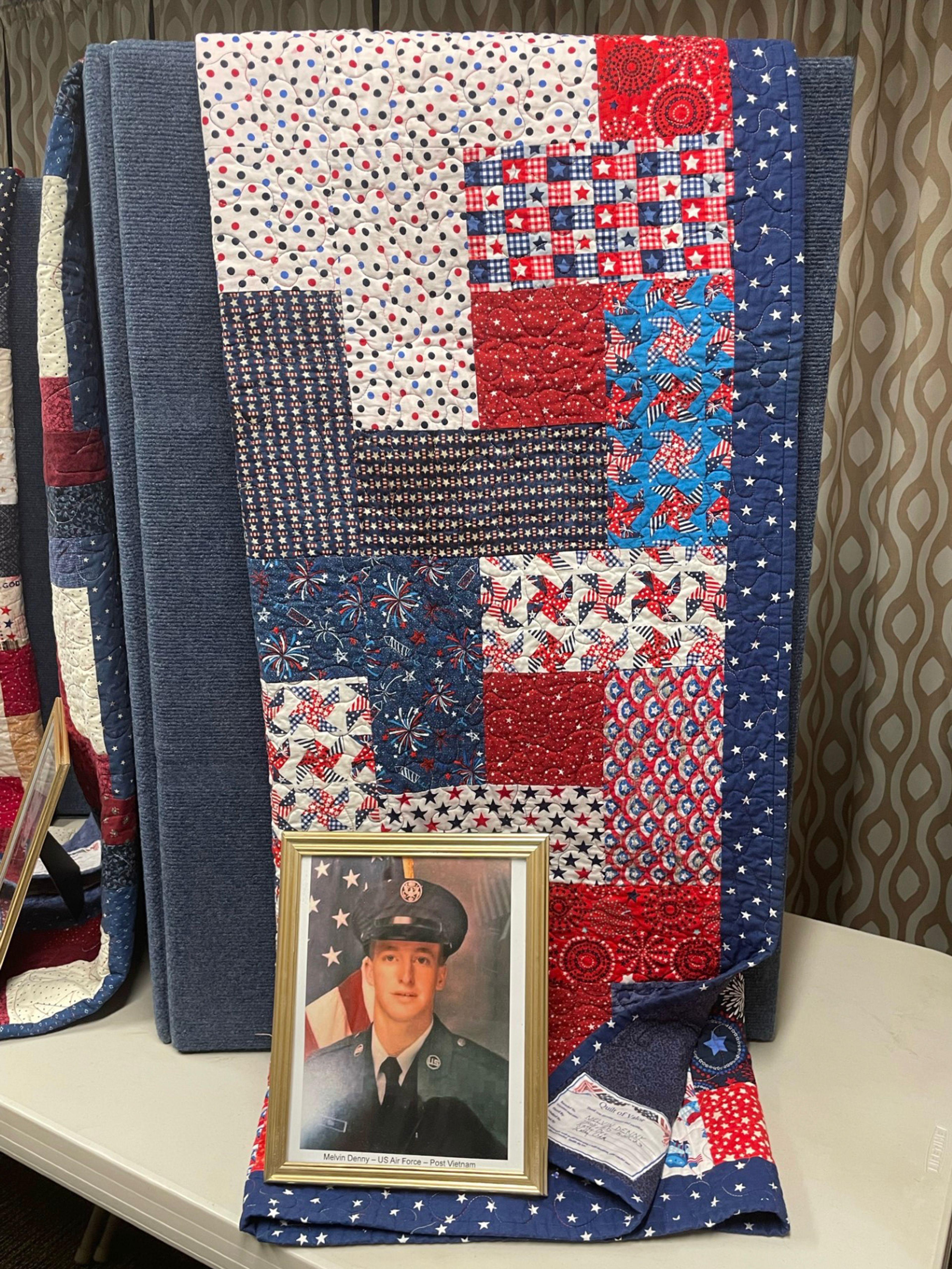 A picture of Melvin Denny, Air Force, sits with his quilt of valor.