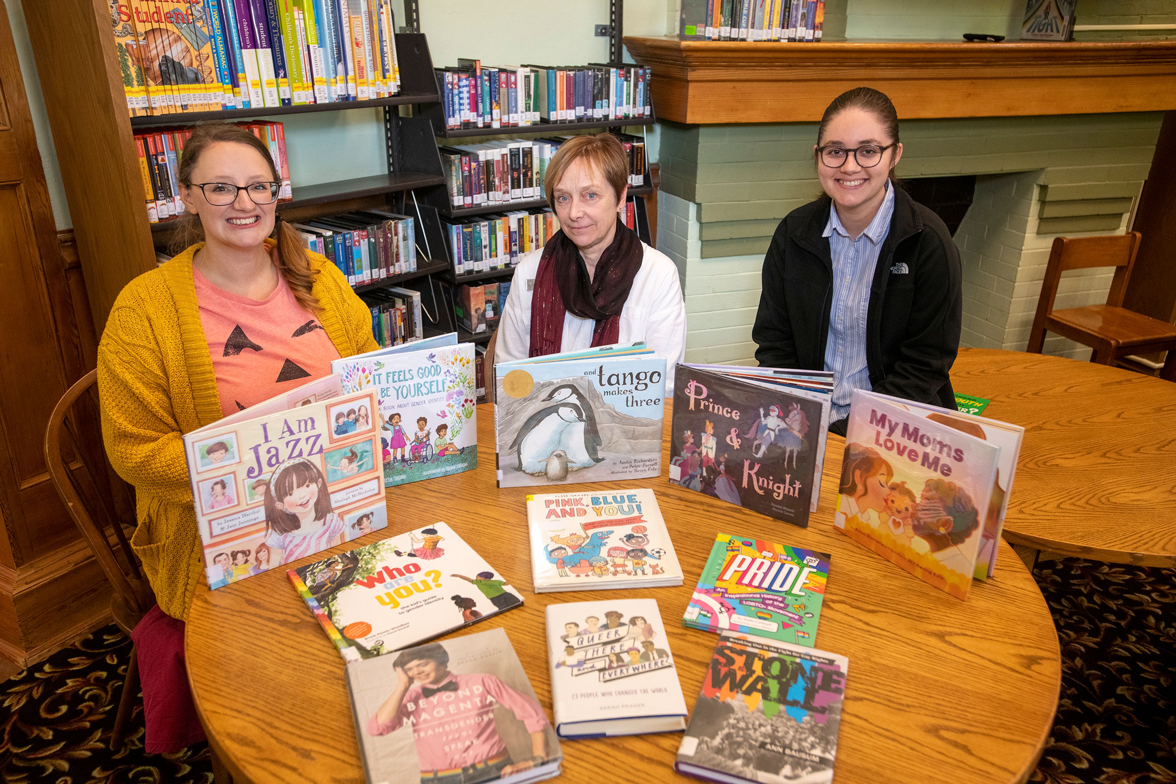 Stacie Echanove, youth services manager, from left, Chris Sokol, director, and Rebecca Rivapalacio, adult services manager, sit behind a variety of books consisting of juvenile nonfiction, young adult and picture books at the Moscow Public Library.