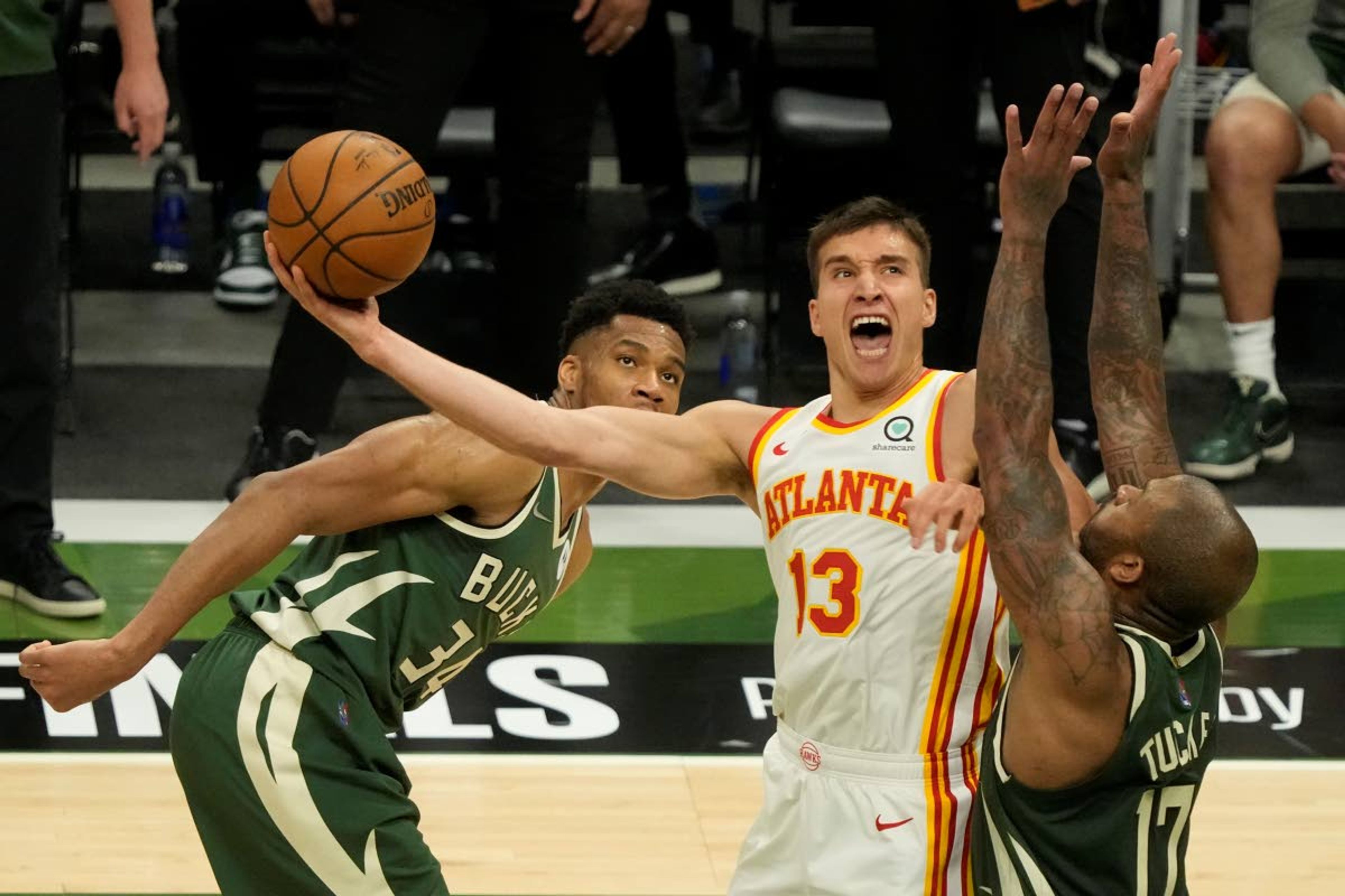 Atlanta Hawks' Bogdan Bogdanovic shoots between Milwaukee Bucks' P.J. Tucker and Giannis Antetokounmpo during the second half of Game 1 of the NBA Eastern Conference basketball finals game Wednesday, June 23, 2021, in Milwaukee. (AP Photo/Morry Gash)