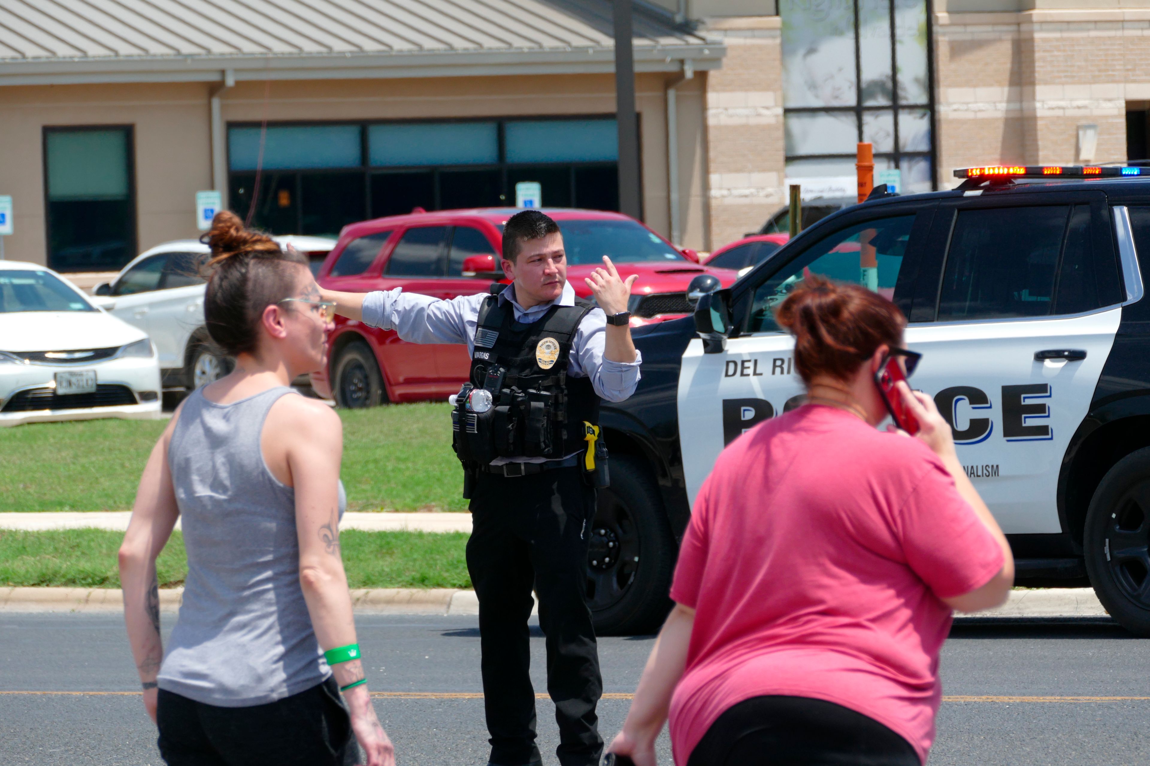 A law enforcement officer helps people cross the street at Uvalde Memorial Hospital after a shooting was reported earlier in the day at Robb Elementary School, Tuesday, May 24, 2022, in Uvalde, Texas. (Billy Calzada/The San Antonio Express-News via AP)