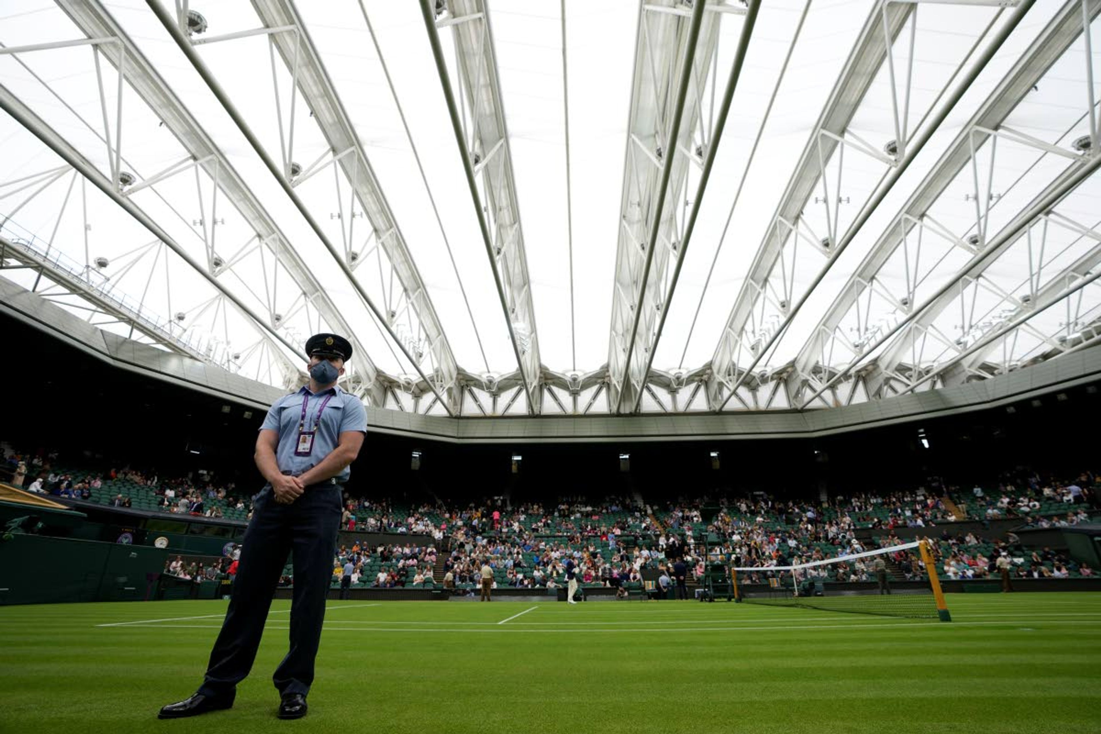 A steward stands on Centre Court covered with the roof ahead of the men's singles match between Serbia's Novak Djokovic and Britain's Jack Draper on day one of the Wimbledon Tennis Championships in London, Monday June 28, 2021. (AP Photo/Kirsty Wigglesworth)