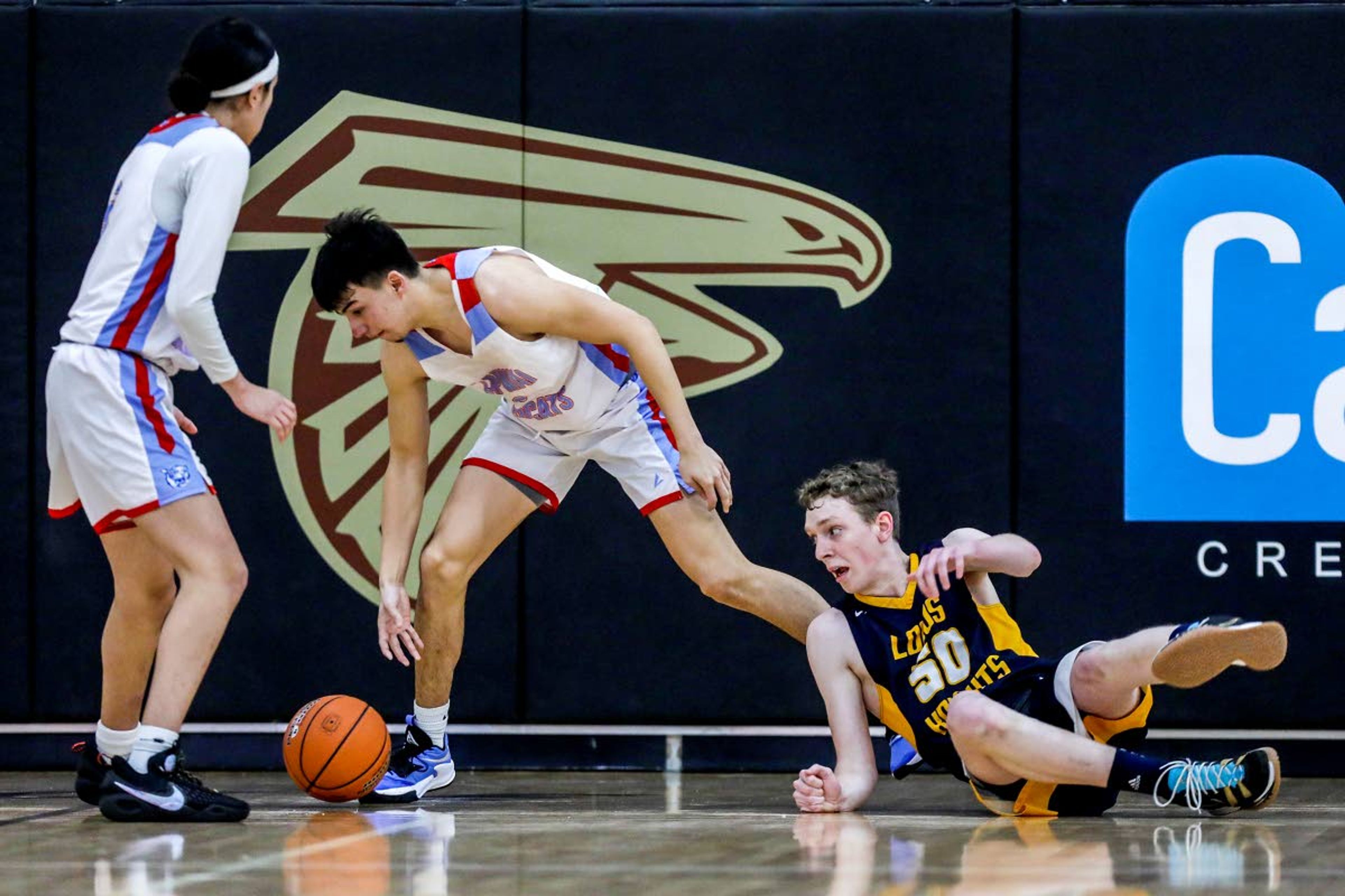 Logos Ben Druffel hits the ground as Lapwai guard Kross Taylor takes possession of the ball during round two of the Idaho High School boys state basketball tournament at Vallivue High School on Friday.