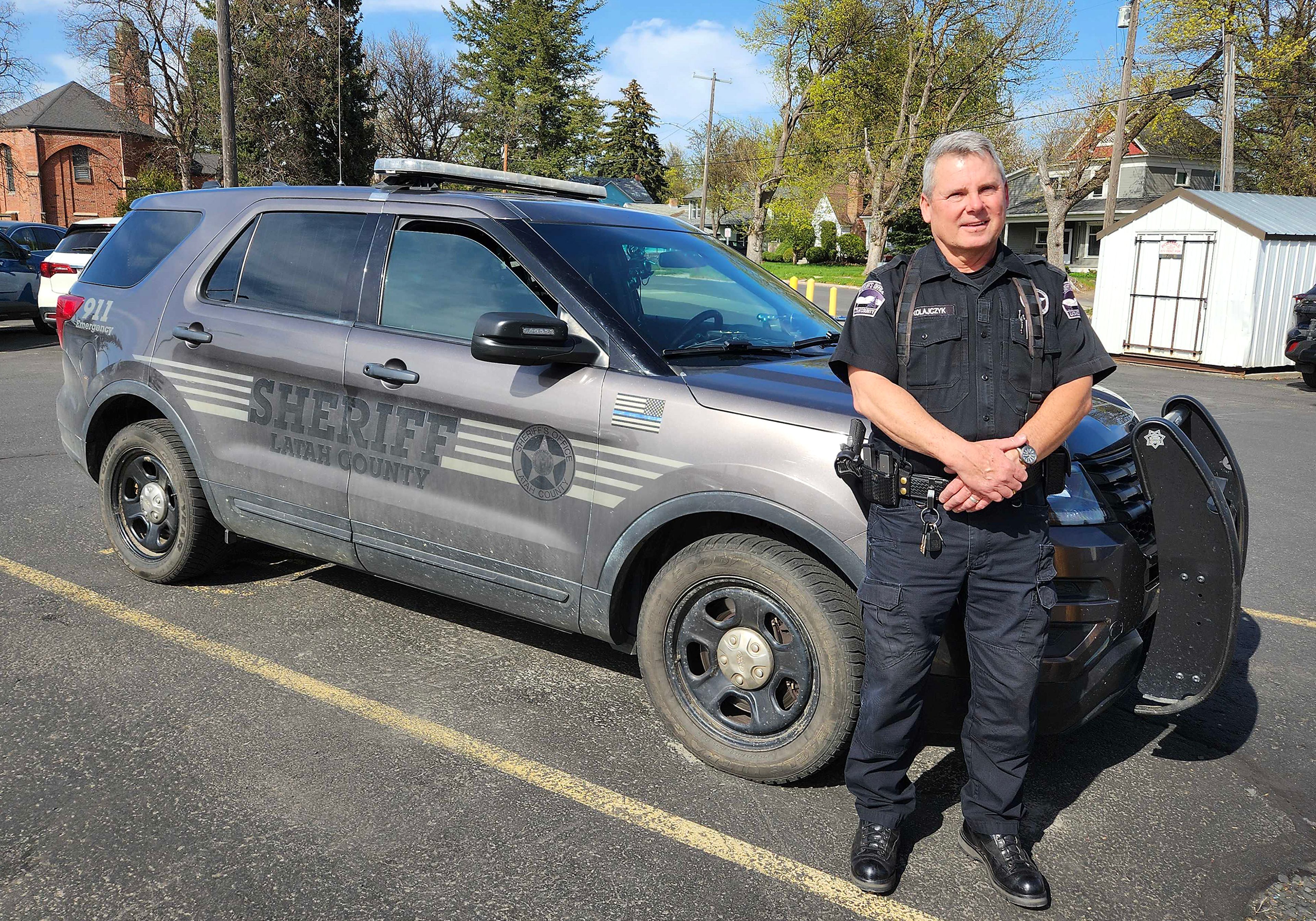 Latah County Deputy Scott Mikolajczyk retiring after 28 years with the county, stands in front of his police vehicle for a photo Monday.