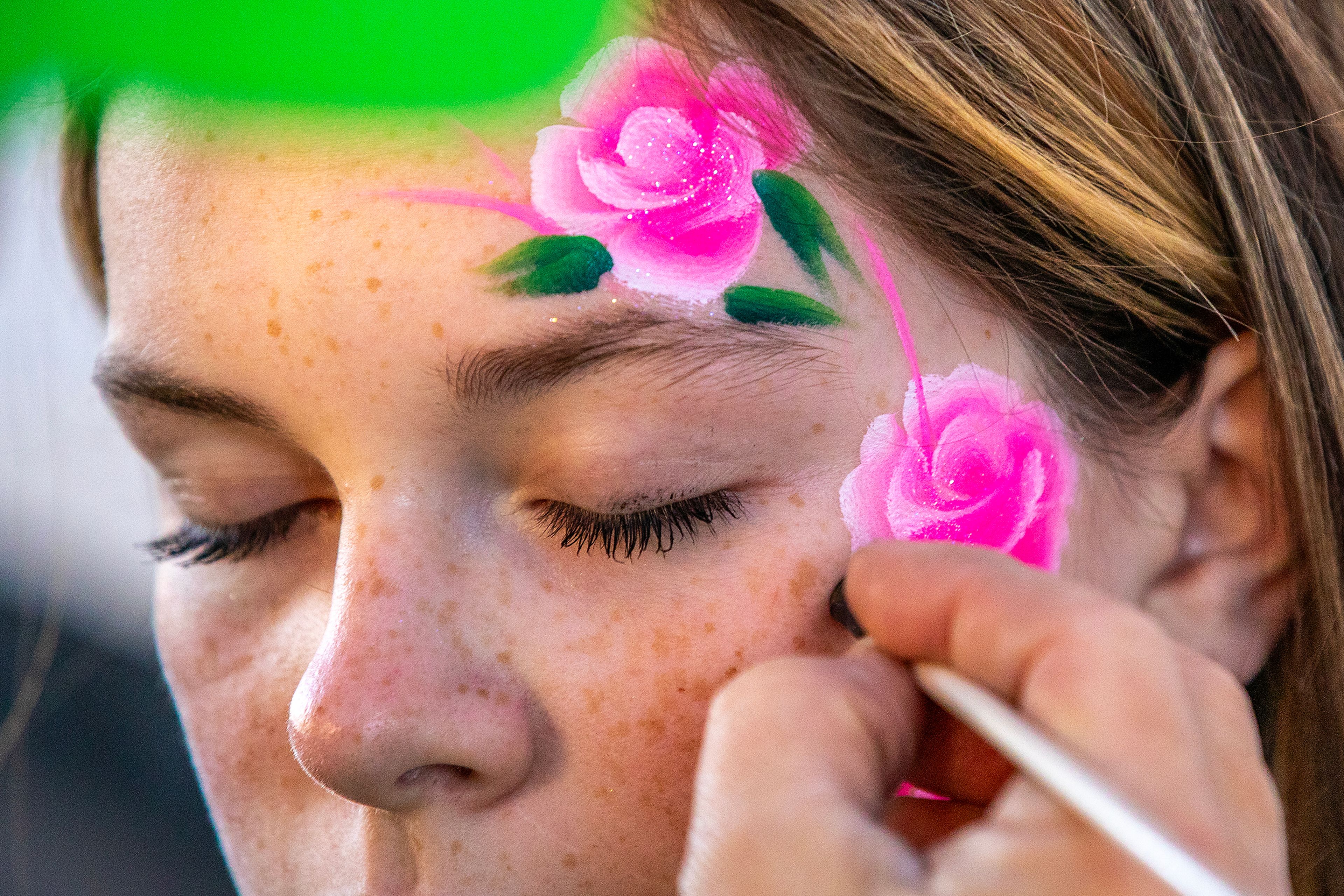 Paisley Miller, 12, of Lewiston, has roses painted on her face by Kimberly Bunch of Fish Kiss Face Art Saturday at Pumpkin Palooza in downtown Lewiston.,