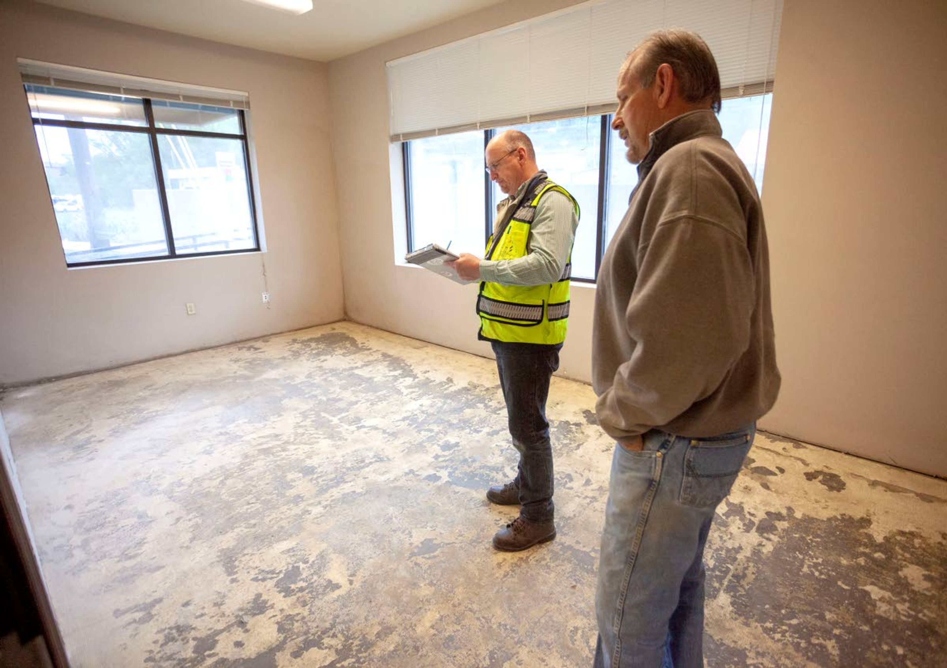 Pullman Building Inspector Allen Luke, talks to building owner Parley Pearce while inspecting new drywall at the Tractor Town Square building on Wednesday in Pullman. The building was damaged when Missouri Flat Creek flooded in April.