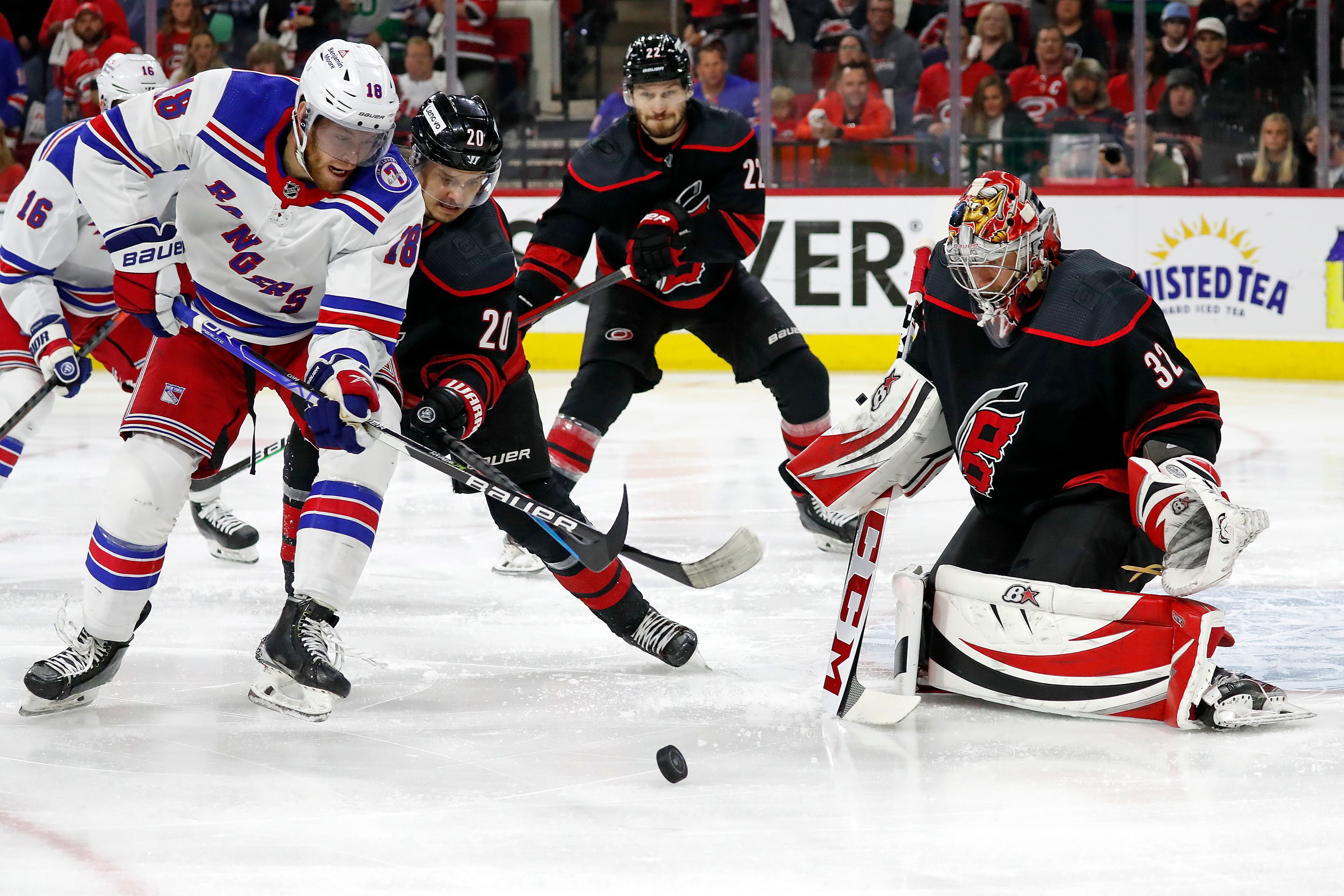 New York Rangers' Andrew Copp (18) battles for the puck with Carolina Hurricanes' Sebastian Aho (20) in front of Hurricanes goaltender Antti Raanta (32) with Hurricanes Brett Pesce (22) nearby during the first period of Game 7 of an NHL hockey Stanley Cup second-round playoff series in Raleigh, N.C., Monday, May 30, 2022. (AP Photo/Karl B DeBlaker)